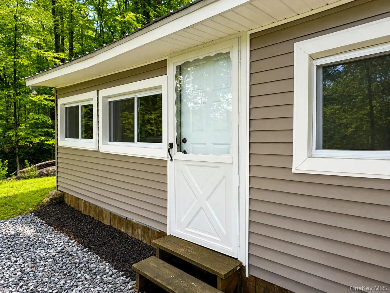 Exterior featuring tan horizontal siding, white trim, and a white storm door with a decorative kick plate Exterior featuring tan horizontal siding, white trim, and a white storm door with a decorative kick plate
