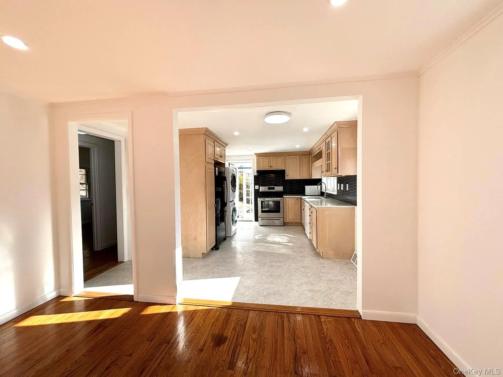 Kitchen featuring stainless steel range, light brown cabinets, backsplash, and light hardwood / wood-style floors Kitchen featuring stainless steel range, light brown cabinets, backsplash, and light hardwood / wood-style floors