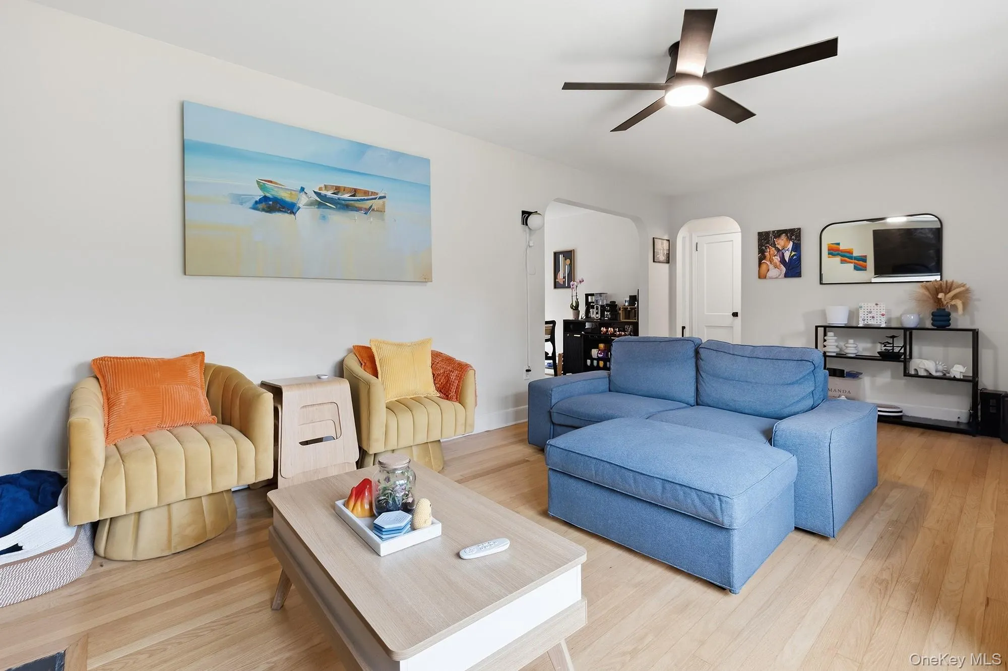 Living area featuring wood-finish flooring, a modern ceiling fan with integrated lighting, and light-colored walls Living area featuring wood-finish flooring, a modern ceiling fan with integrated lighting, and light-colored walls