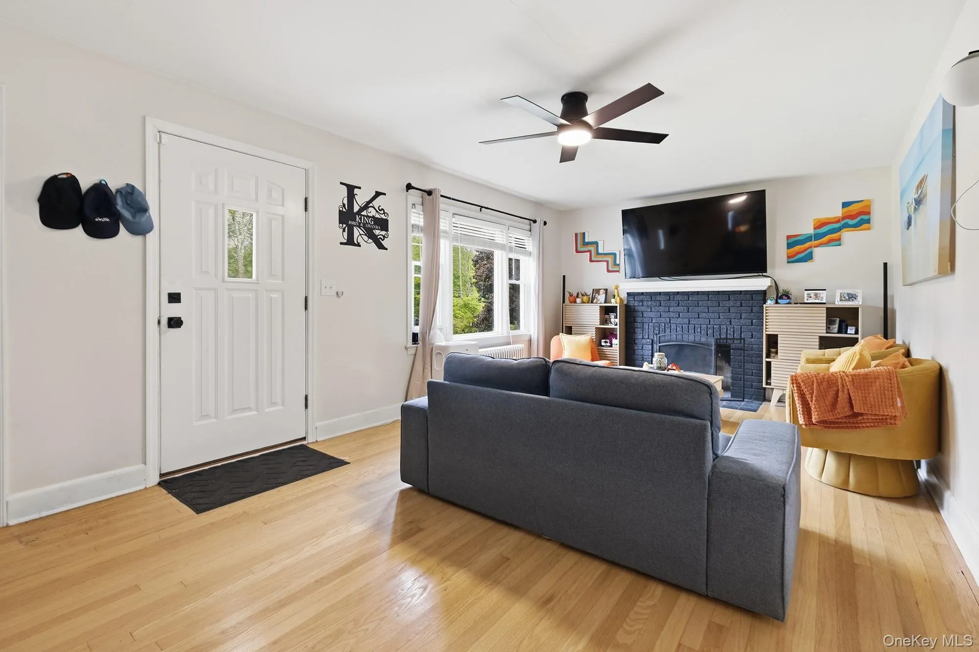Bright and open living room showcasing hardwood flooring, a contemporary ceiling fan, and a comfortable gray upholstered sofa Bright and open living room showcasing hardwood flooring, a contemporary ceiling fan, and a comfortable gray upholstered sofa