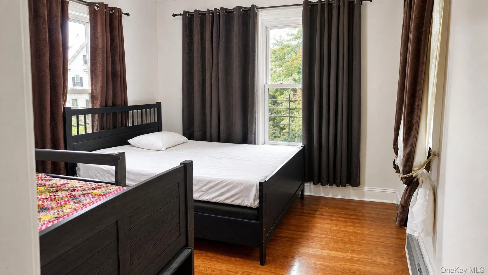 Hardwood-finish flooring highlights this room with white walls and baseboards Hardwood-finish flooring highlights this room with white walls and baseboards
