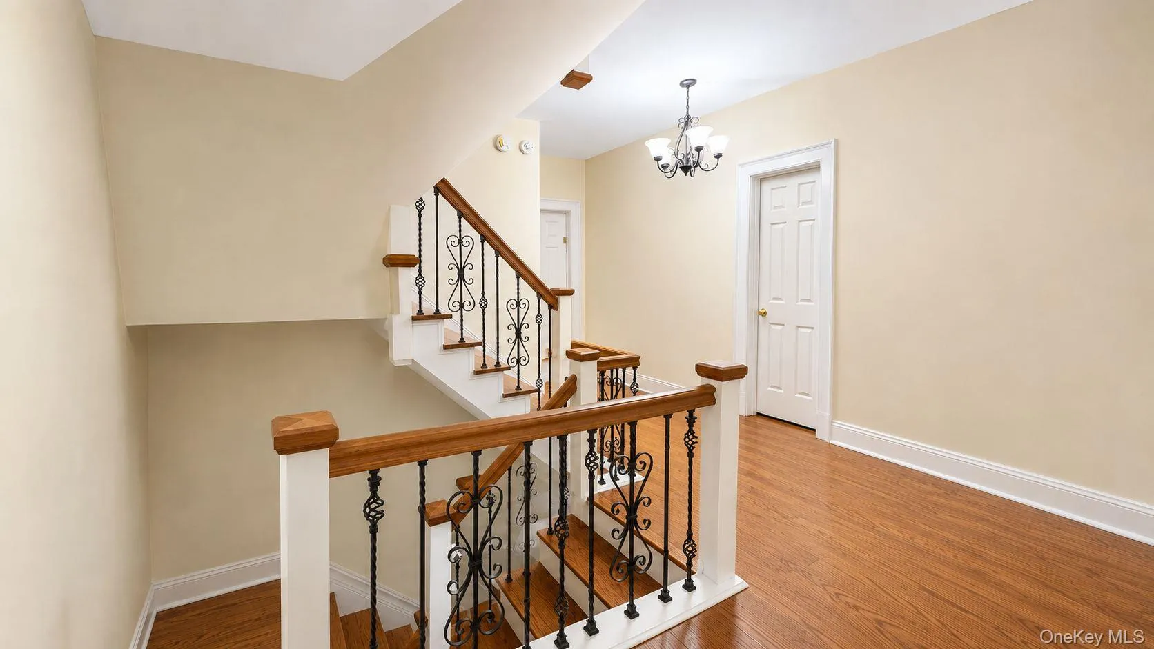 Staircase featuring wood treads, white risers, and wrought iron balusters with wood handrails Staircase featuring wood treads, white risers, and wrought iron balusters with wood handrails