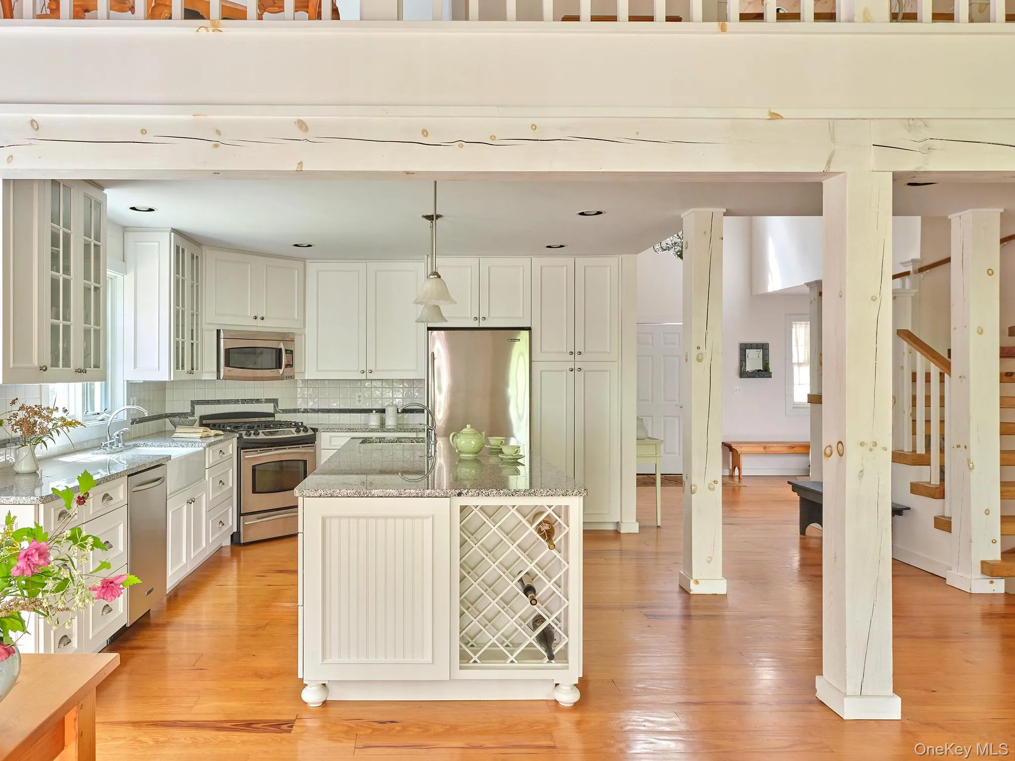 Kitchen featuring glass insert cabinets, light stone countertops, hanging light fixtures, backsplash, and appliances with stainless steel finishes Kitchen featuring glass insert cabinets, light stone countertops, hanging light fixtures, backsplash, and appliances with stainless steel finishes