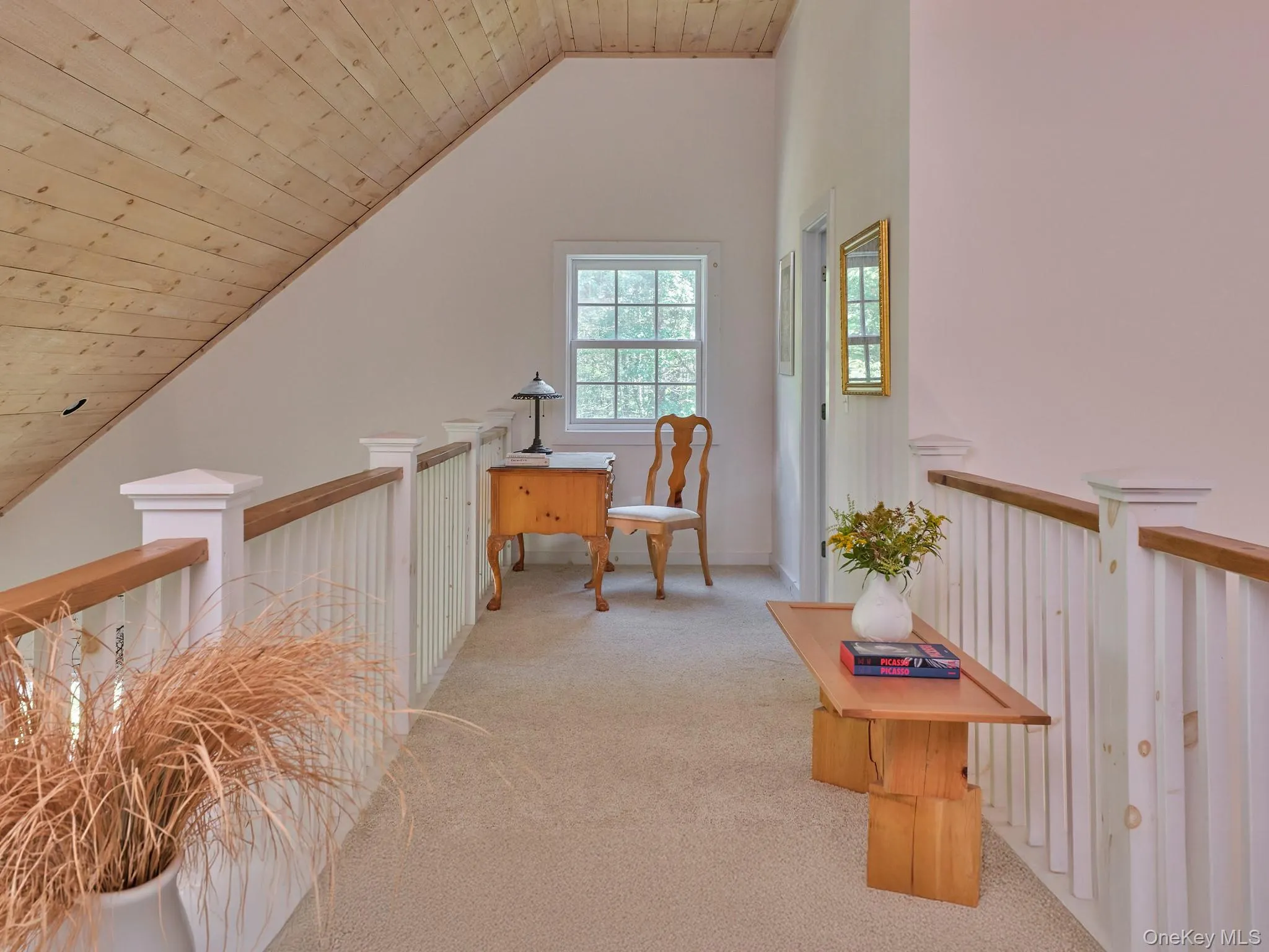 Corridor featuring wooden ceiling, vaulted ceiling, light colored carpet, and an upstairs landing Corridor featuring wooden ceiling, vaulted ceiling, light colored carpet, and an upstairs landing