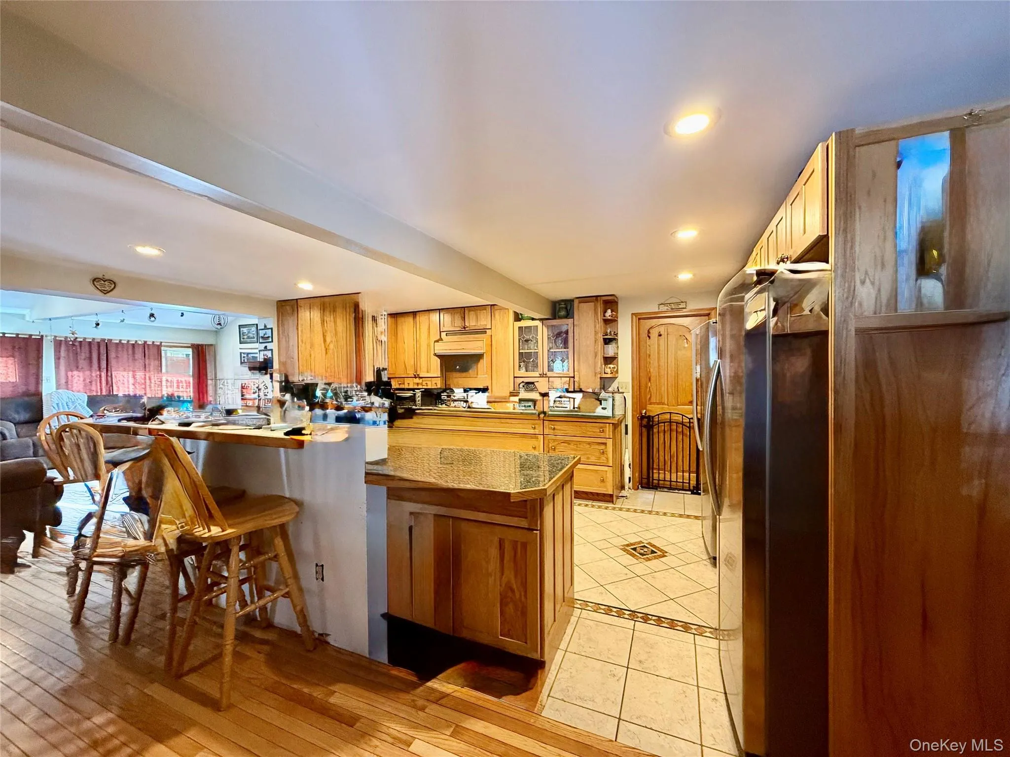 Kitchen featuring freestanding refrigerator, a breakfast bar, recessed lighting, wood finish cabinets, and a peninsula Kitchen featuring freestanding refrigerator, a breakfast bar, recessed lighting, wood finish cabinets, and a peninsula