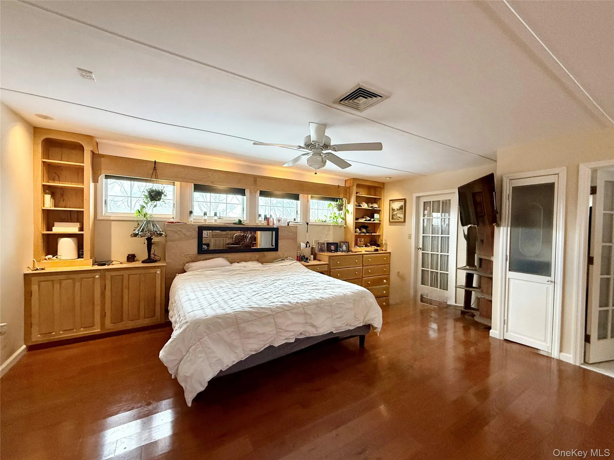 Bedroom with multiple windows, wood finished floors, and a ceiling fan Bedroom with multiple windows, wood finished floors, and a ceiling fan