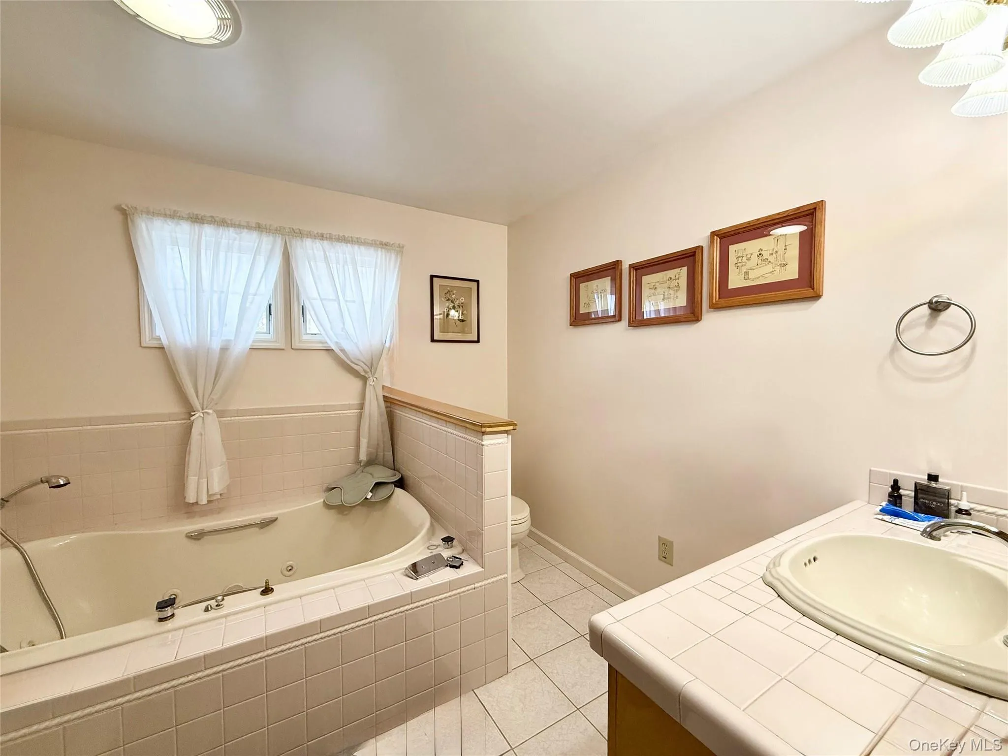 Full bathroom with vanity, a jetted tub, and light tile patterned flooring Full bathroom with vanity, a jetted tub, and light tile patterned flooring