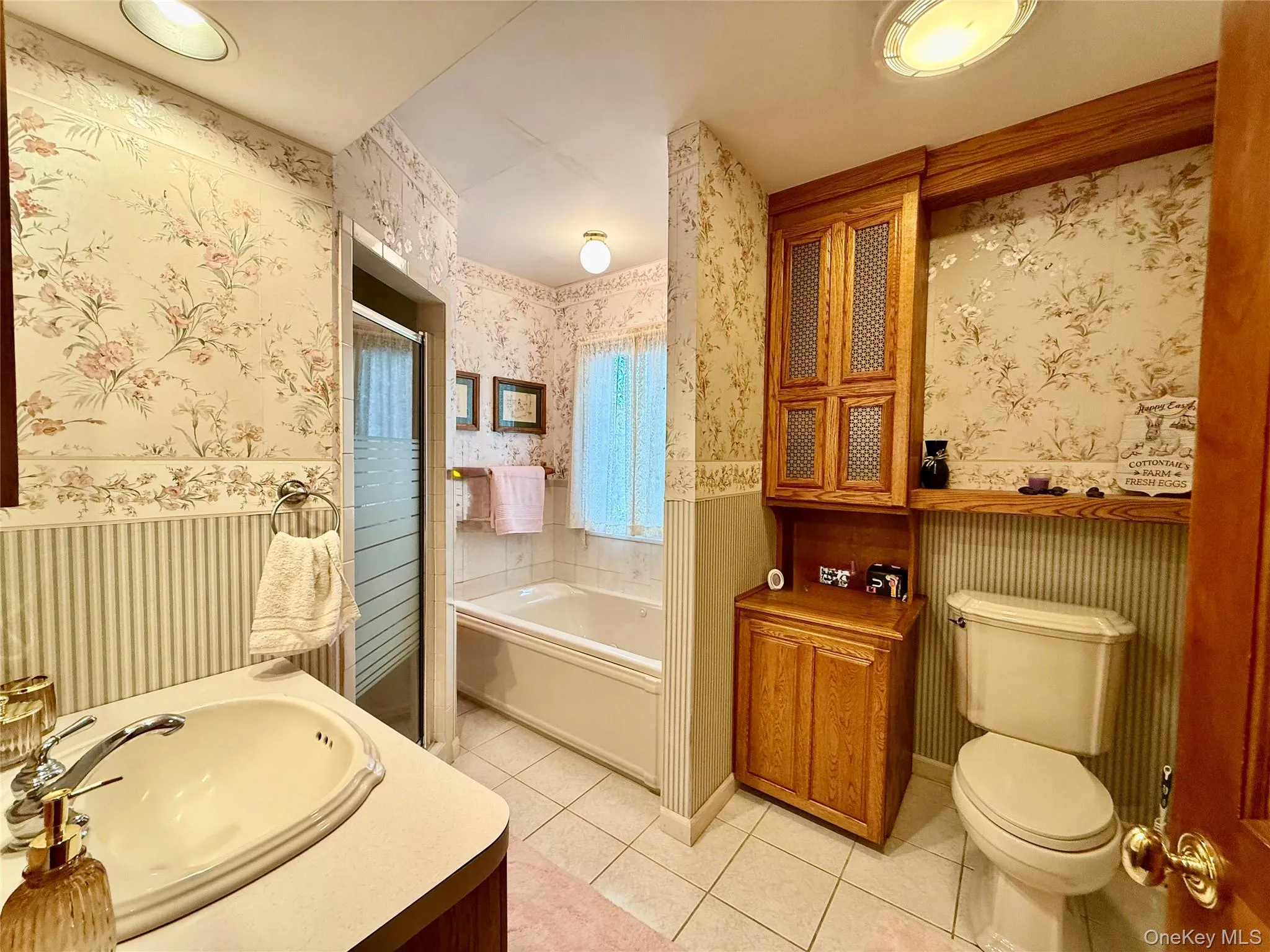 Bathroom with wallpapered walls, vanity, a soaking bath, light tile patterned floors, and a shower stall Bathroom with wallpapered walls, vanity, a soaking bath, light tile patterned floors, and a shower stall