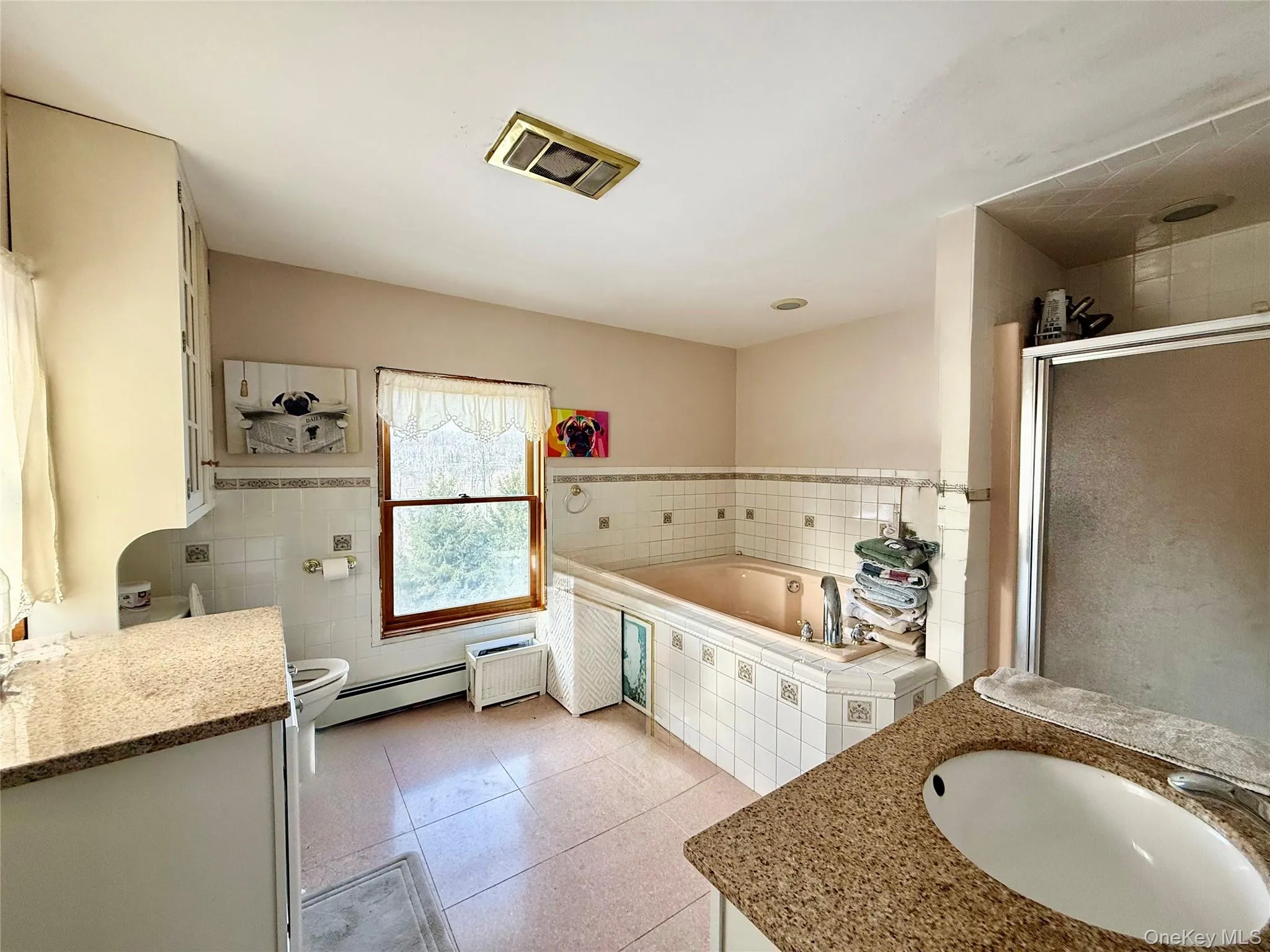 Kitchen featuring white cabinets, baseboard heating, and light tile patterned flooring Kitchen featuring white cabinets, baseboard heating, and light tile patterned flooring