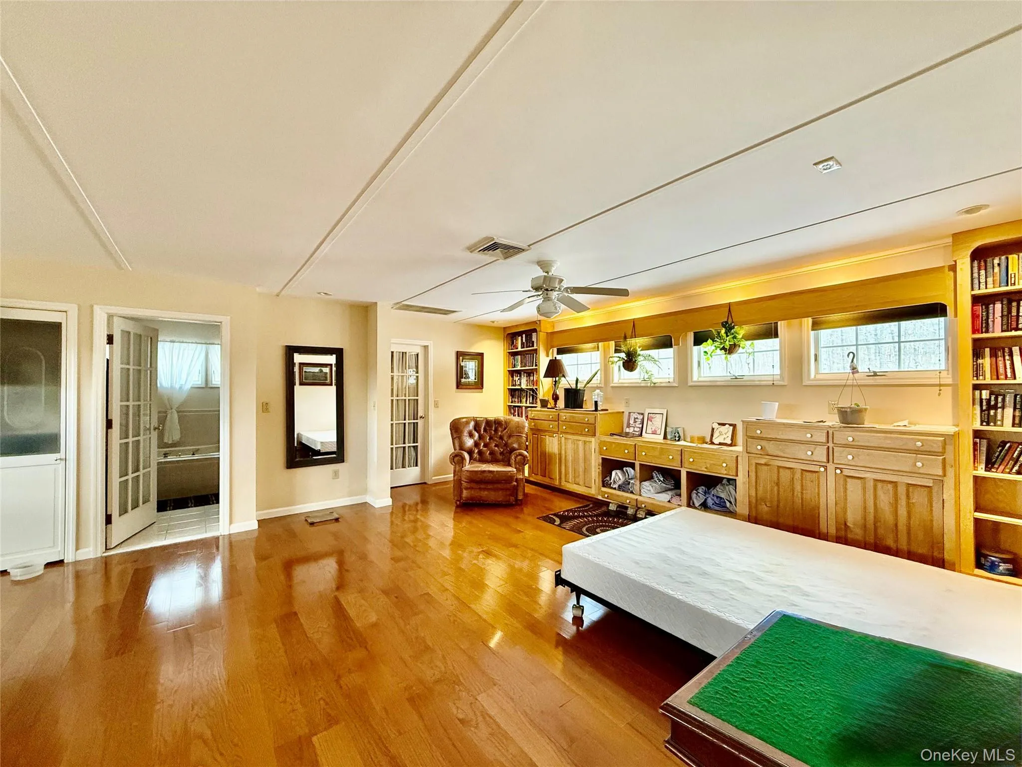 Bedroom featuring light wood finished floors, ensuite bathroom, and ceiling fan Bedroom featuring light wood finished floors, ensuite bathroom, and ceiling fan
