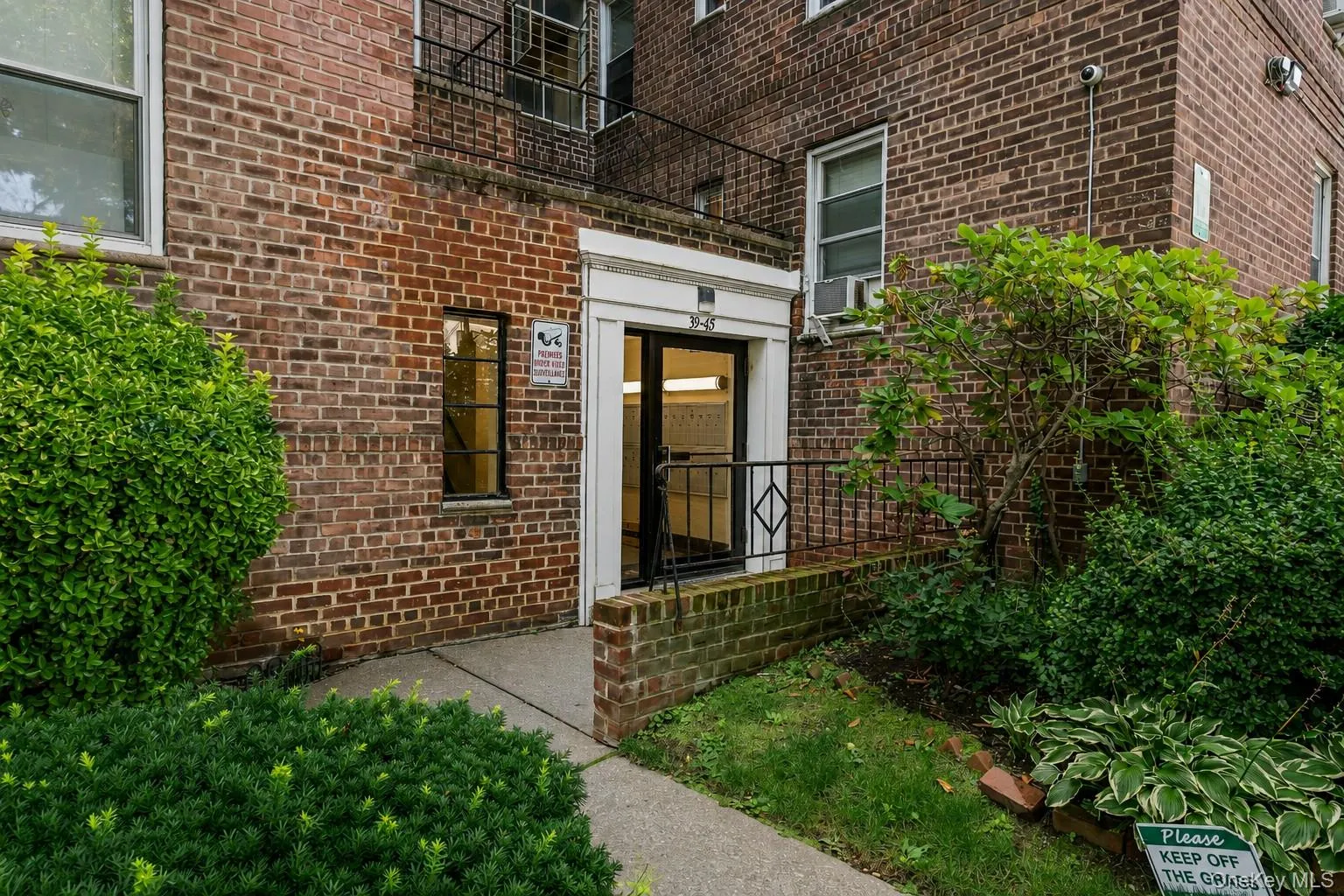 Brick exterior building with a white-trimmed entrance featuring a black metal railing Brick exterior building with a white-trimmed entrance featuring a black metal railing