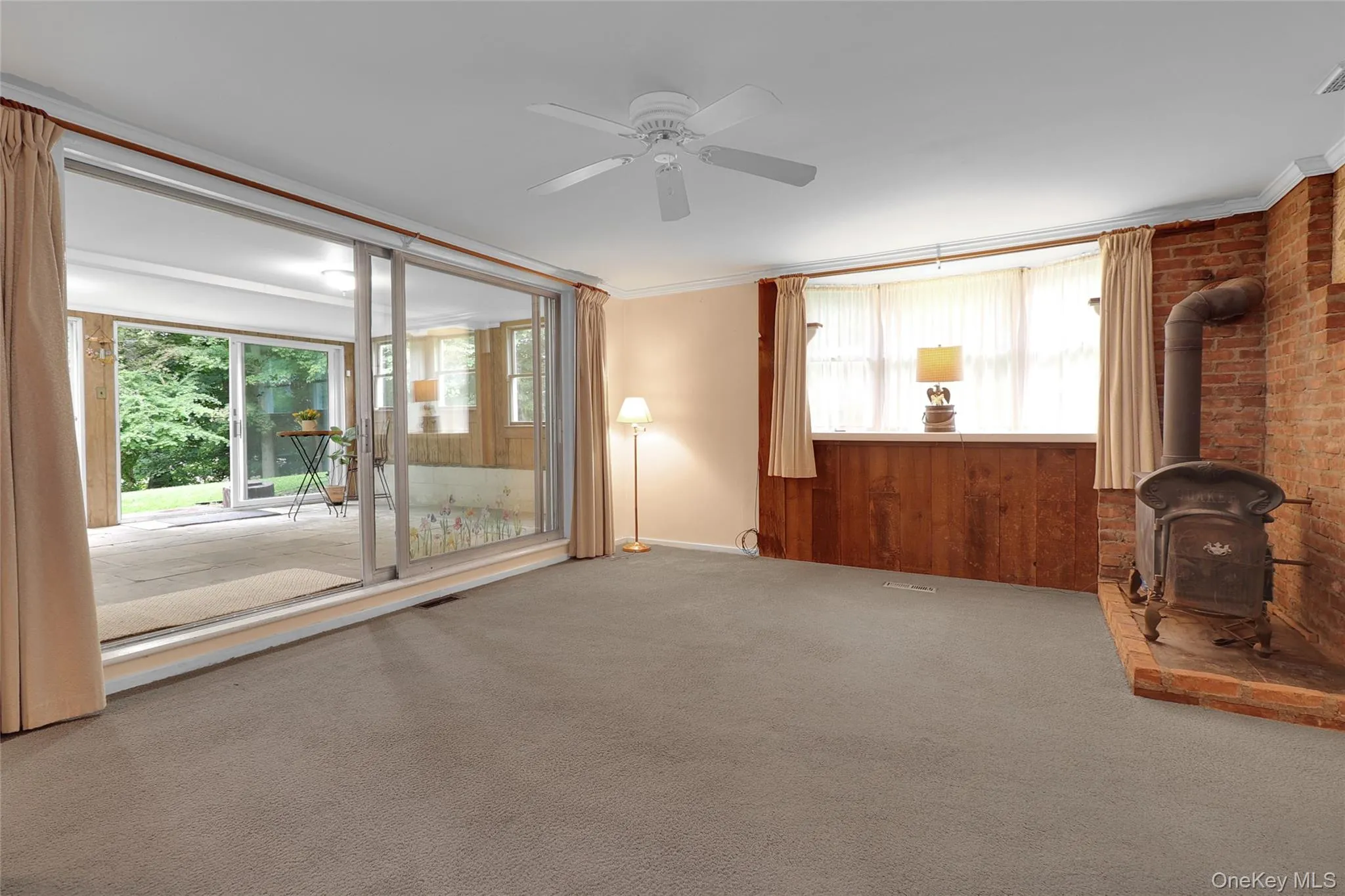 Living room with large window, wood burning stove, sliding glass doors to sunroom Living room with large window, wood burning stove, sliding glass doors to sunroom