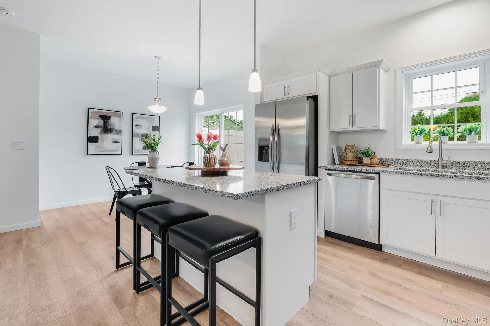 Kitchen with stainless steel appliances, a center island, light stone countertops, and light wood finished floors Kitchen with stainless steel appliances, a center island, light stone countertops, and light wood finished floors