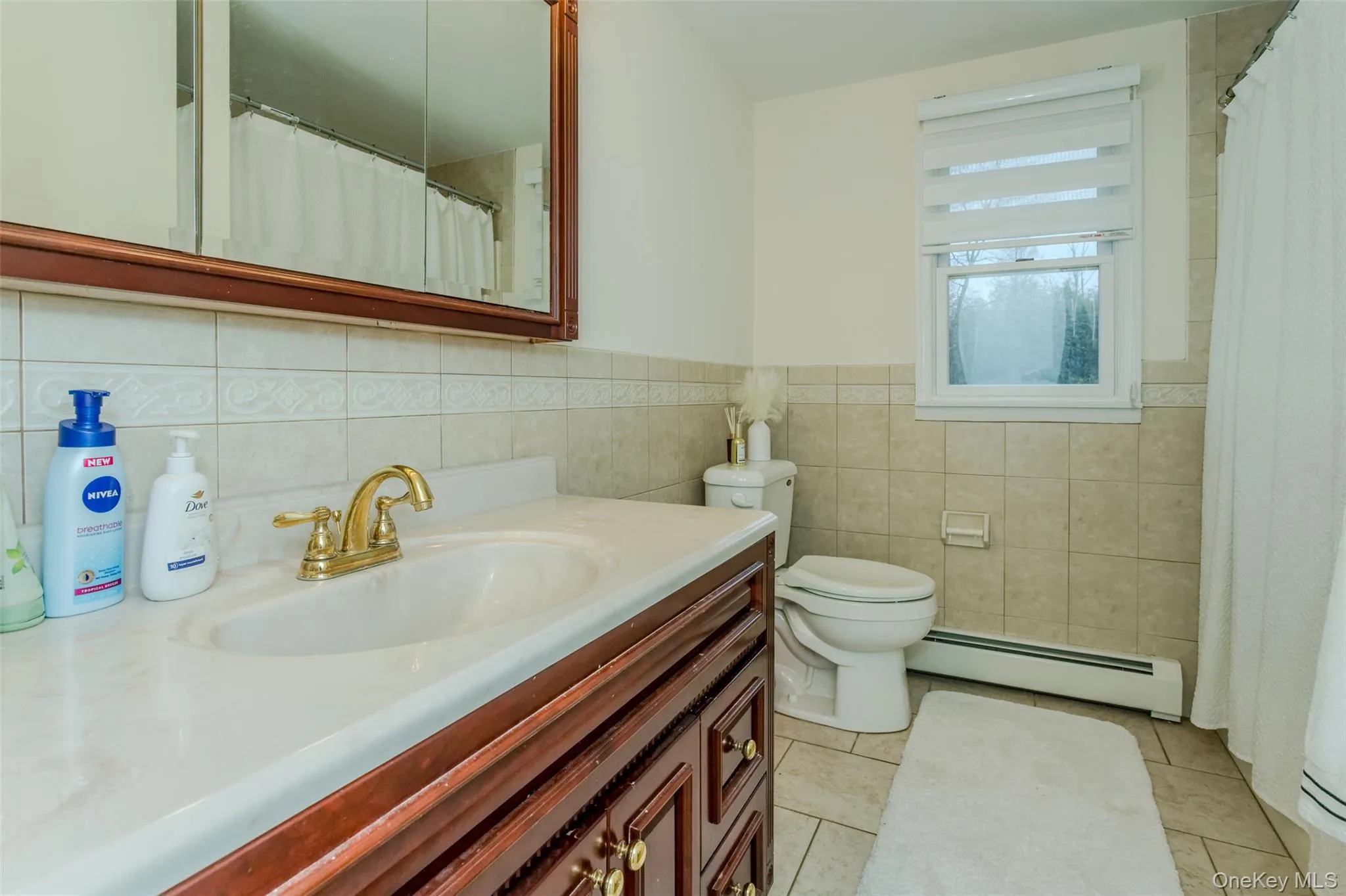 Bathroom with vanity, tile patterned flooring, toilet, baseboard heating, and tile walls Bathroom with vanity, tile patterned flooring, toilet, baseboard heating, and tile walls