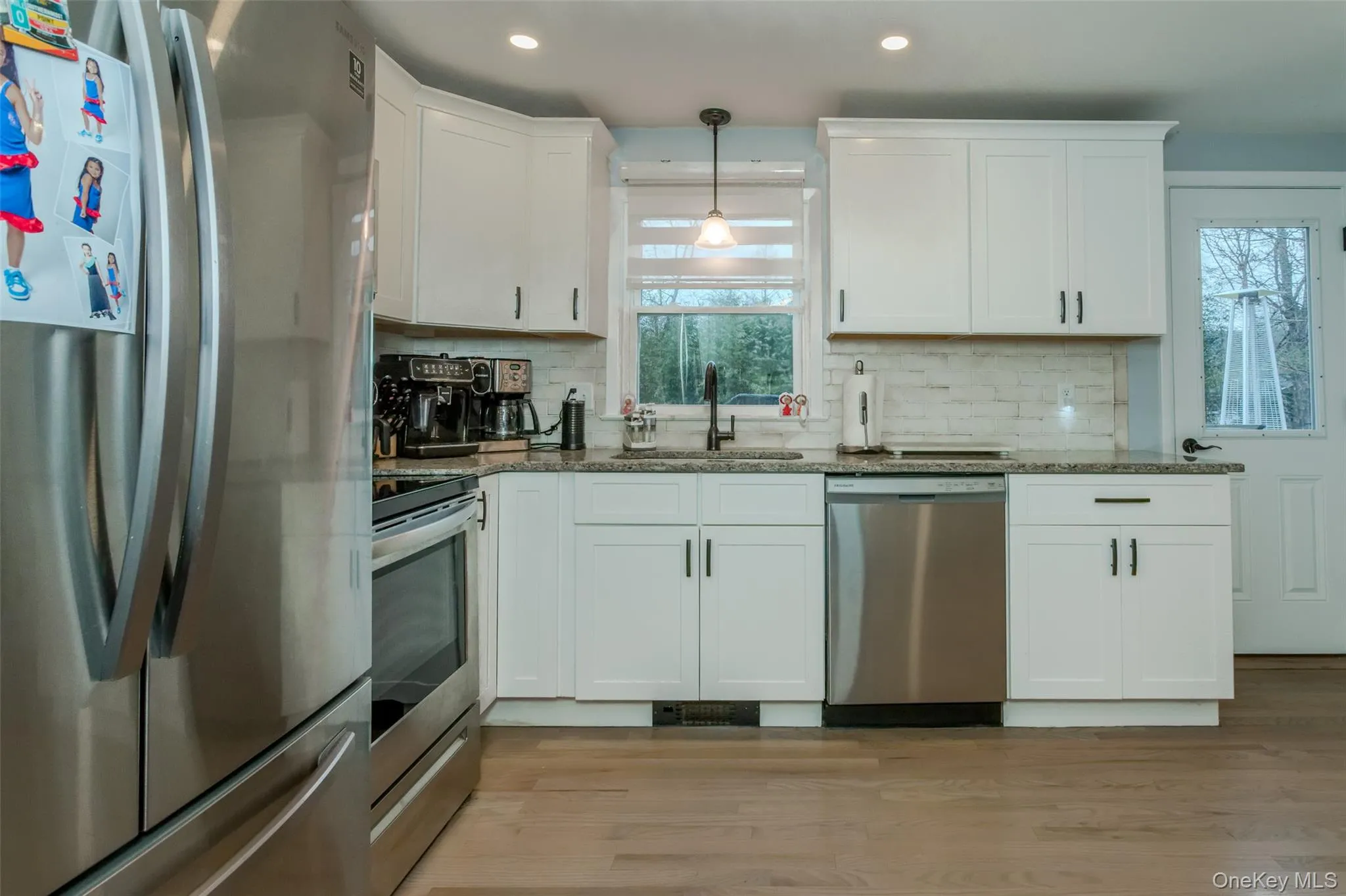 Kitchen with light hardwood / wood-style flooring, white cabinets, a healthy amount of sunlight, and appliances with stainless steel finishes Kitchen with light hardwood / wood-style flooring, white cabinets, a healthy amount of sunlight, and appliances with stainless steel finishes