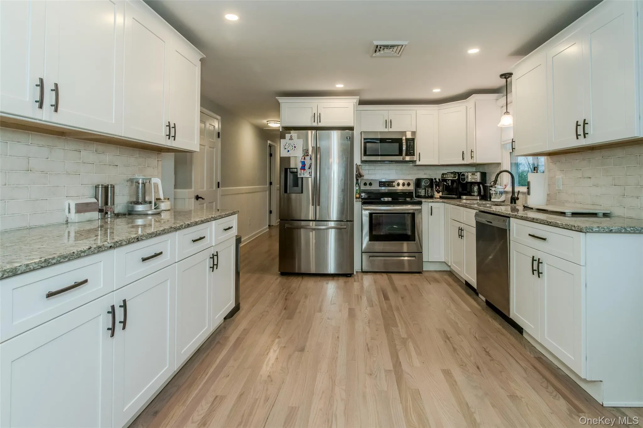 Kitchen featuring white cabinets, stainless steel appliances, light hardwood / wood-style floors, and sink Kitchen featuring white cabinets, stainless steel appliances, light hardwood / wood-style floors, and sink