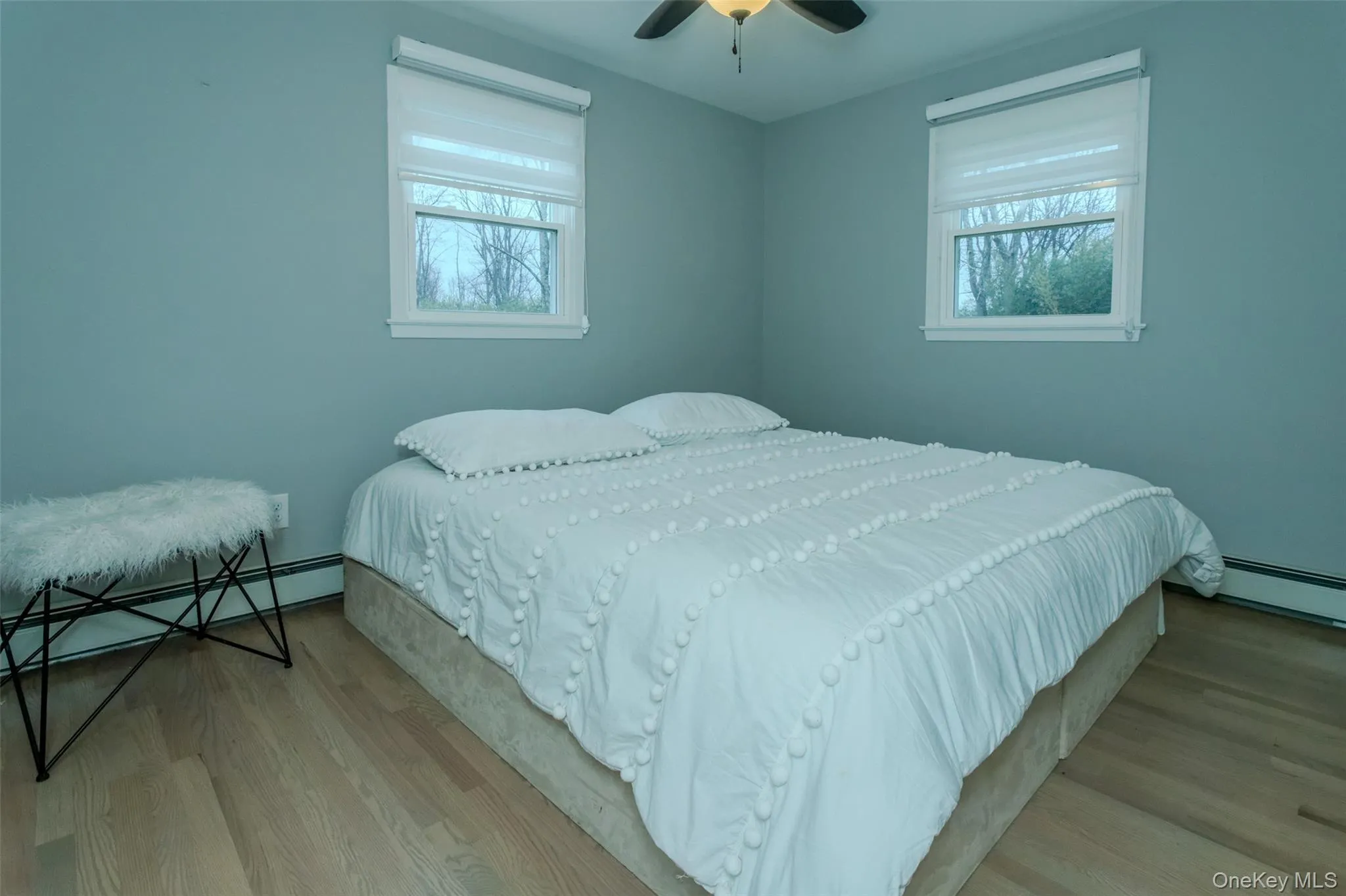 Bedroom with ceiling fan, light hardwood / wood-style floors, baseboard heating, and multiple windows Bedroom with ceiling fan, light hardwood / wood-style floors, baseboard heating, and multiple windows