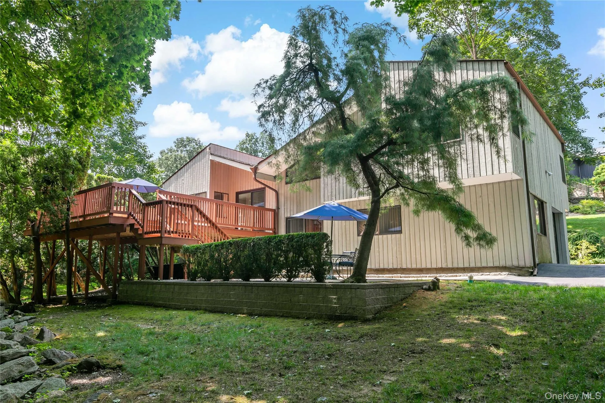 View of spacious backyard with stone patio and large deck. View of spacious backyard with stone patio and large deck.