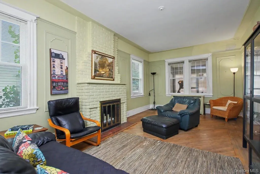 Bright and inviting living room showcasing painted brick walls, hardwood flooring, and abundant natural light from multiple windows Bright and inviting living room showcasing painted brick walls, hardwood flooring, and abundant natural light from multiple windows