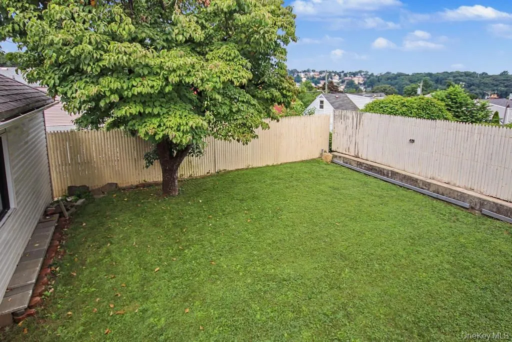 Spacious backyard featuring a level, manicured lawn with mature shade tree and sturdy perimeter fencing Spacious backyard featuring a level, manicured lawn with mature shade tree and sturdy perimeter fencing