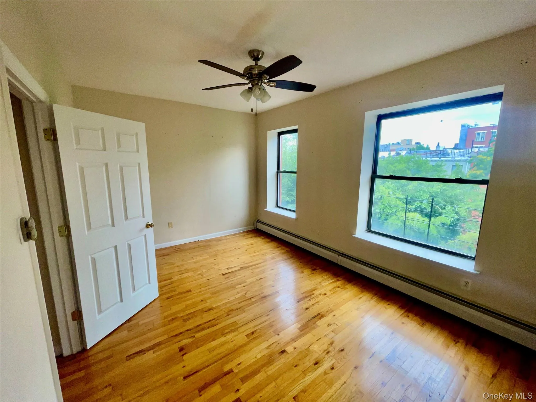 Unfurnished room featuring a baseboard radiator, light wood finished floors, and a ceiling fan Unfurnished room featuring a baseboard radiator, light wood finished floors, and a ceiling fan
