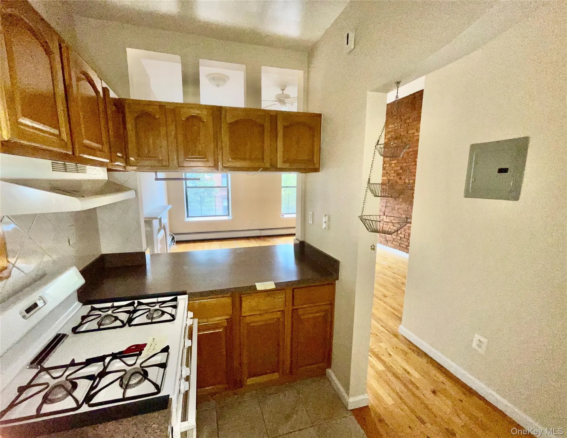 Kitchen with gas range gas stove, brown cabinets, under cabinet range hood, and dark countertops Kitchen with gas range gas stove, brown cabinets, under cabinet range hood, and dark countertops