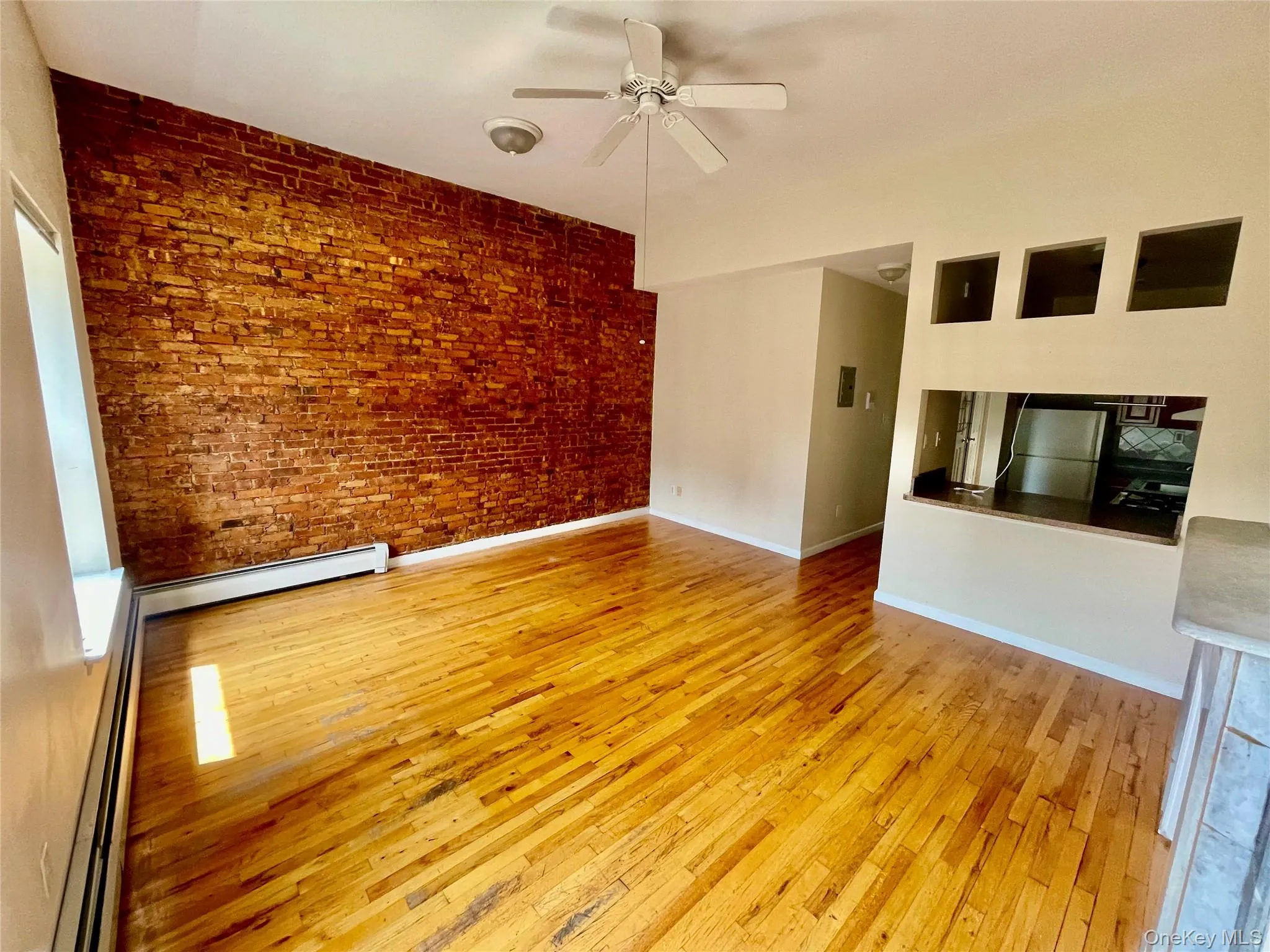 Empty room featuring wood-type flooring, a baseboard heating unit, and ceiling fan Empty room featuring wood-type flooring, a baseboard heating unit, and ceiling fan