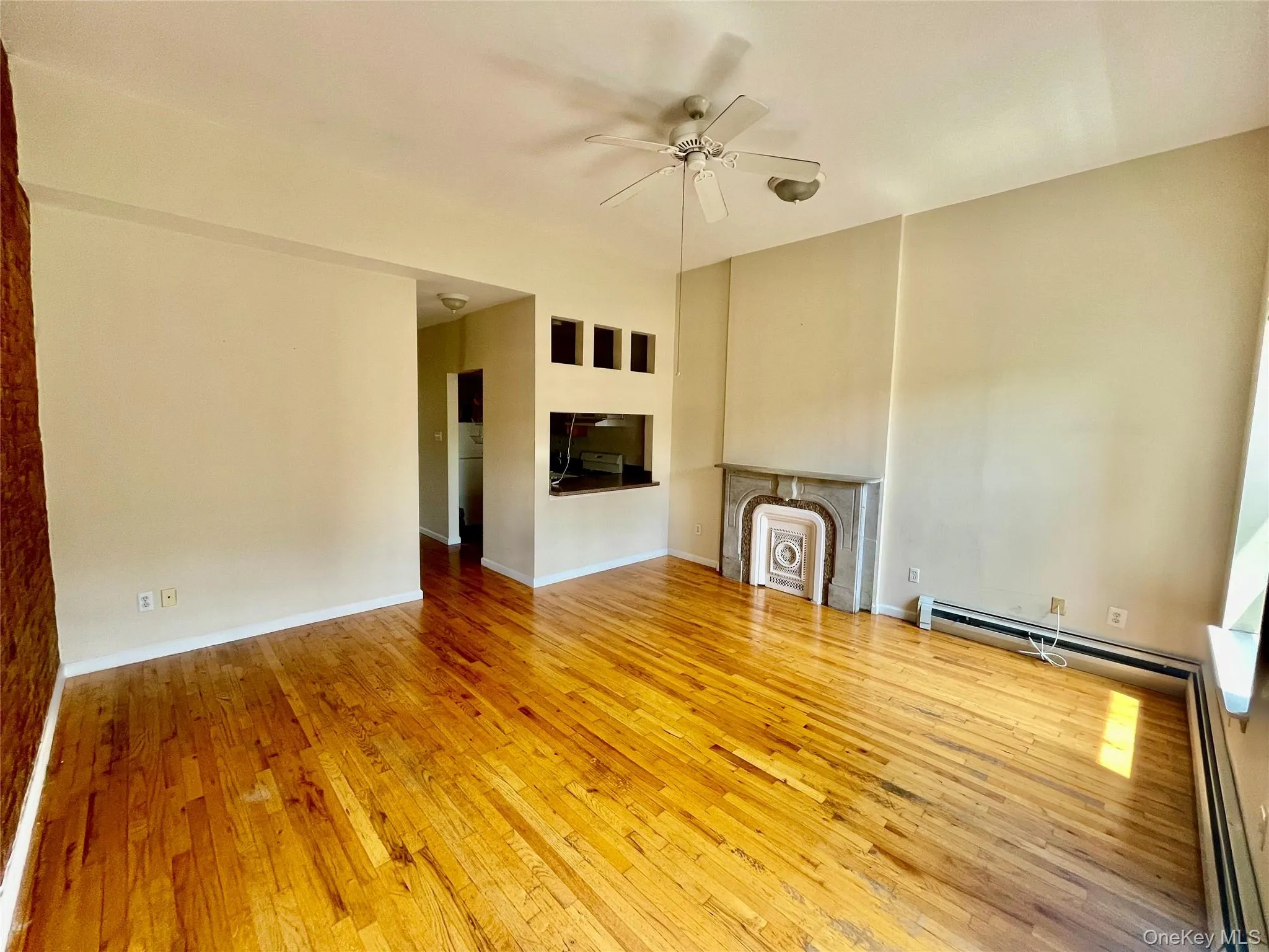 Unfurnished living room featuring ceiling fan, hardwood / wood-style floors, a multi sided fireplace, and baseboard heating Unfurnished living room featuring ceiling fan, hardwood / wood-style floors, a multi sided fireplace, and baseboard heating