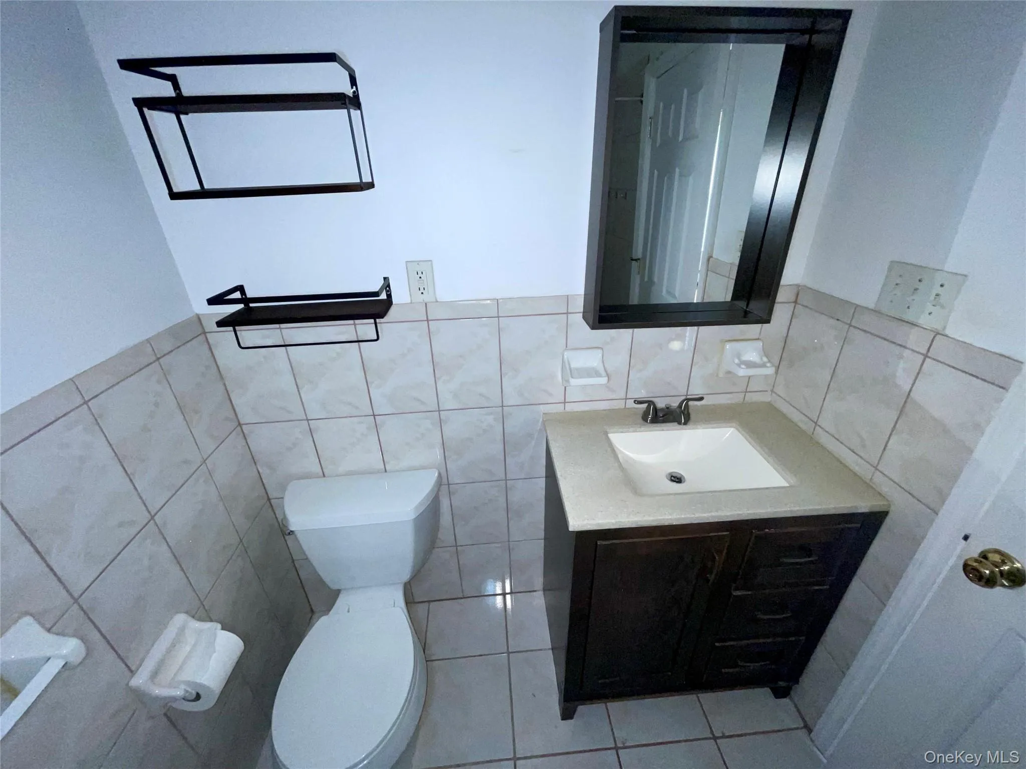 Half bath with vanity, tile walls, a wainscoted wall, and tile patterned floors Half bath with vanity, tile walls, a wainscoted wall, and tile patterned floors