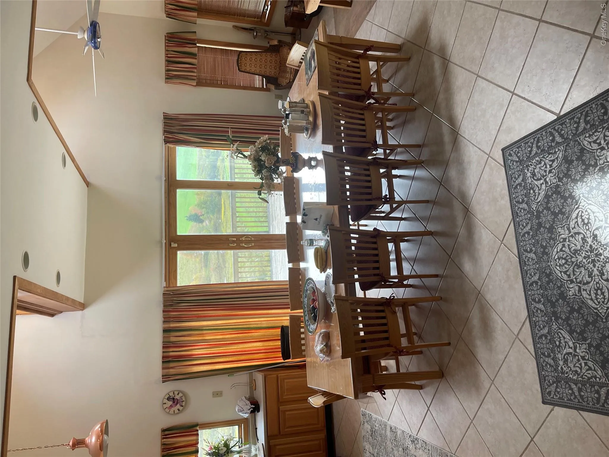 Elegant dining room showcasing vaulted ceilings with skylights, a solid wood dining table with matching spindle-back chairs, and expansive glass doors opening to outdoor space Elegant dining room showcasing vaulted ceilings with skylights, a solid wood dining table with matching spindle-back chairs, and expansive glass doors opening to outdoor space