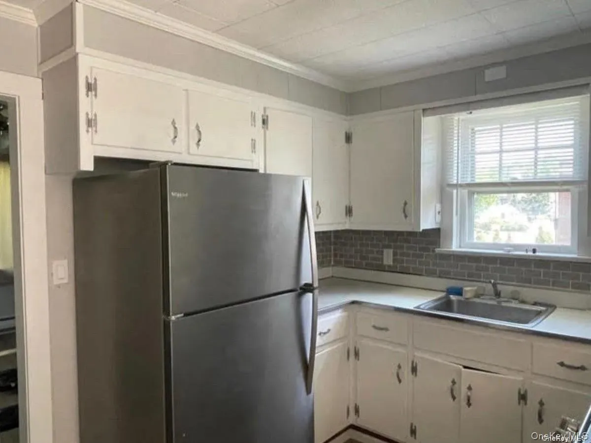 Kitchen with a sink, freestanding refrigerator, ornamental molding, decorative backsplash, and light countertops Kitchen with a sink, freestanding refrigerator, ornamental molding, decorative backsplash, and light countertops