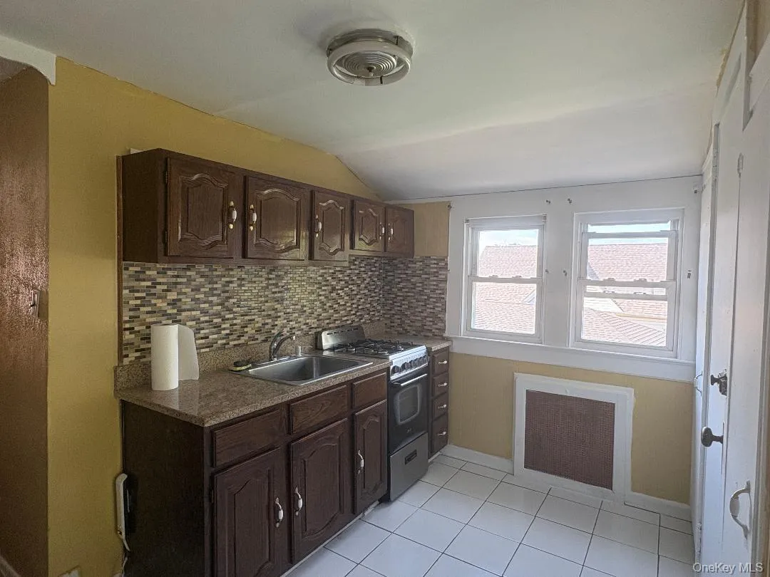 Kitchen featuring wood-finish cabinetry, a mosaic tile backsplash, and a stainless steel gas range Kitchen featuring wood-finish cabinetry, a mosaic tile backsplash, and a stainless steel gas range