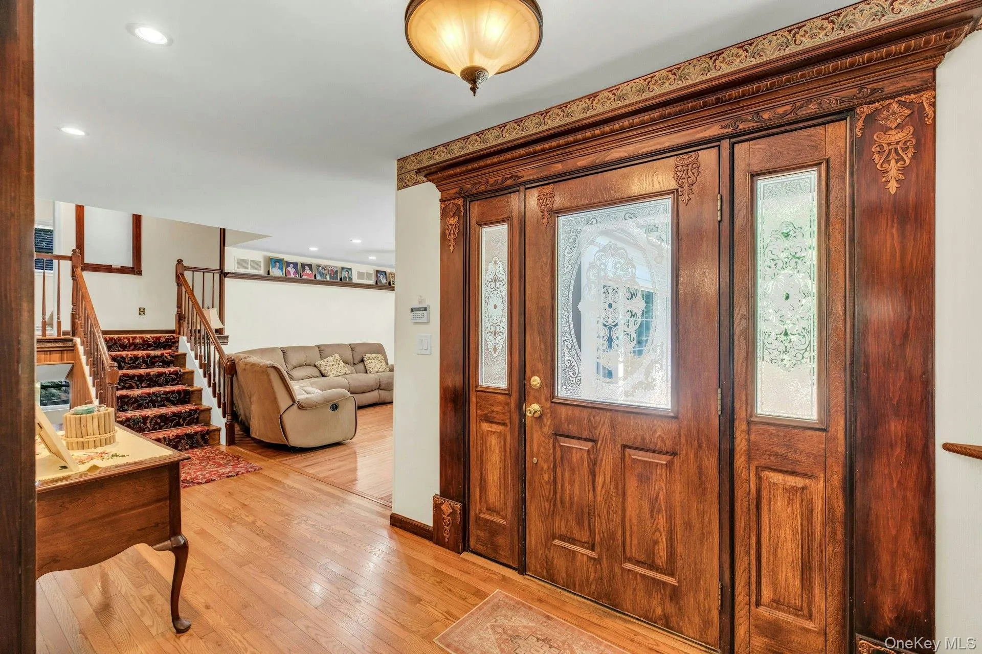 Elegant foyer showcasing ornate wood-paneled double doors with decorative glass inserts and detailed molding Elegant foyer showcasing ornate wood-paneled double doors with decorative glass inserts and detailed molding