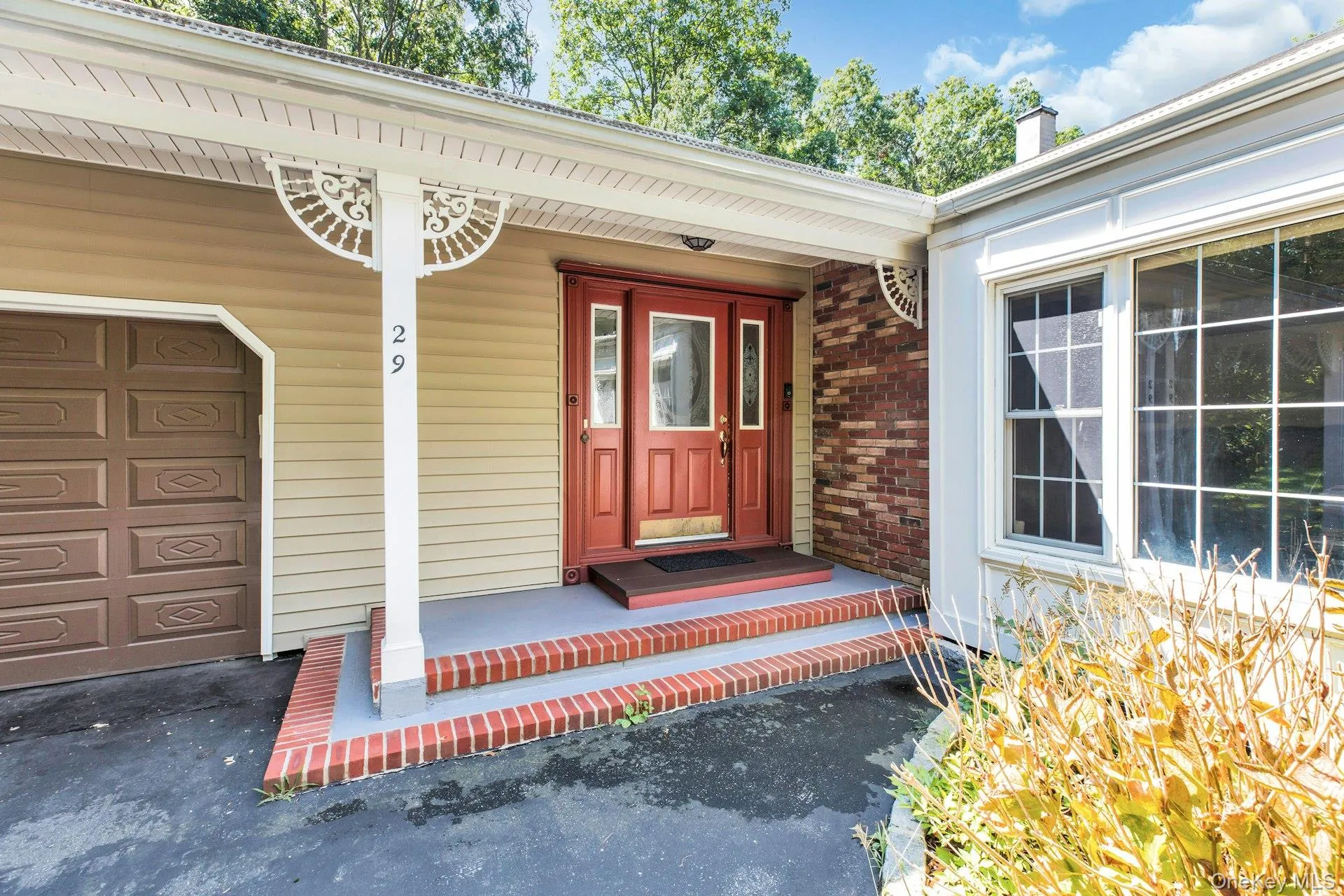 Welcoming front entrance featuring a red double-door entry with sidelights, brick detailing, and stepped brick walkway Welcoming front entrance featuring a red double-door entry with sidelights, brick detailing, and stepped brick walkway