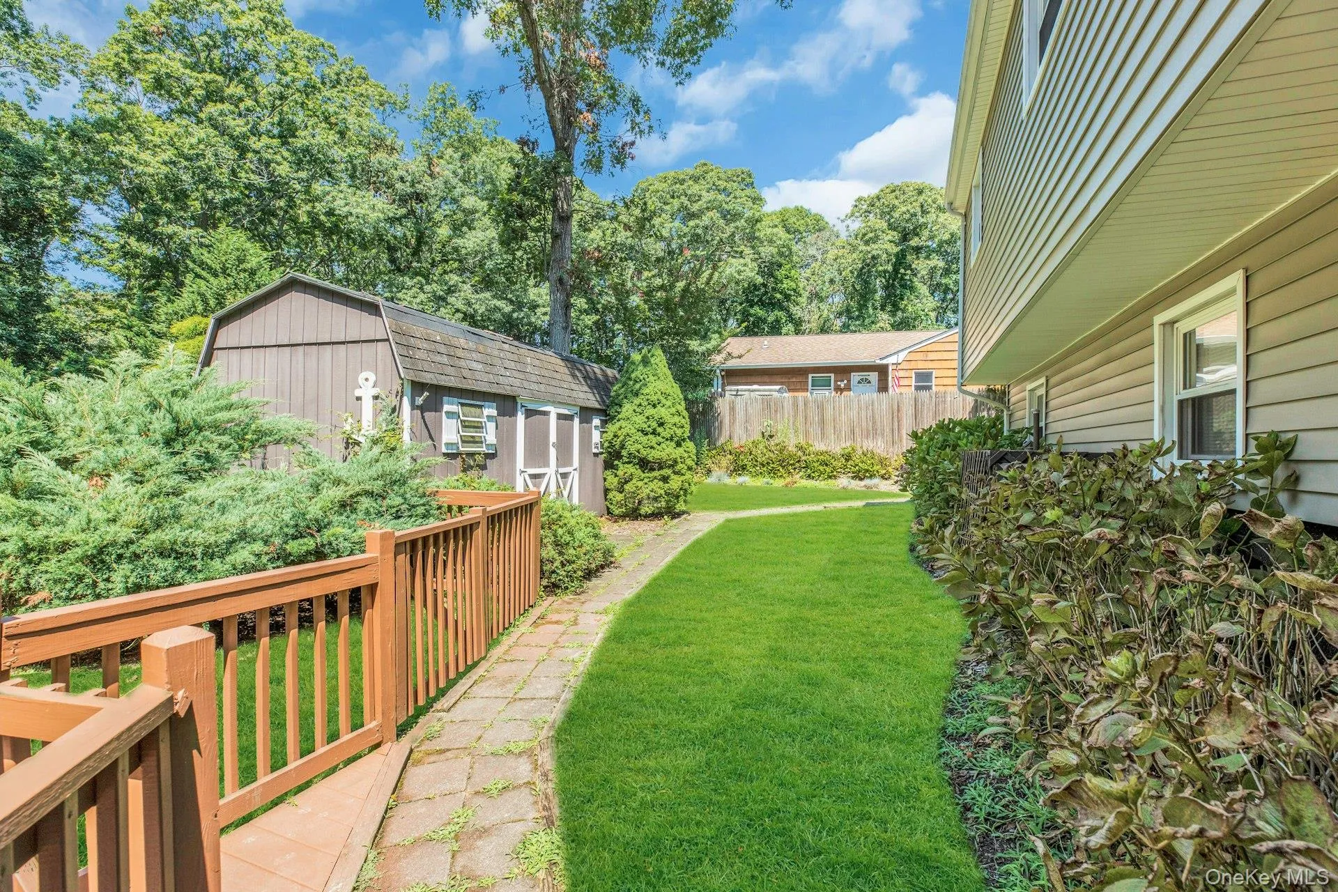 Expansive backyard retreat featuring a manicured lawn, mature tree canopy, and stone paver pathway Expansive backyard retreat featuring a manicured lawn, mature tree canopy, and stone paver pathway