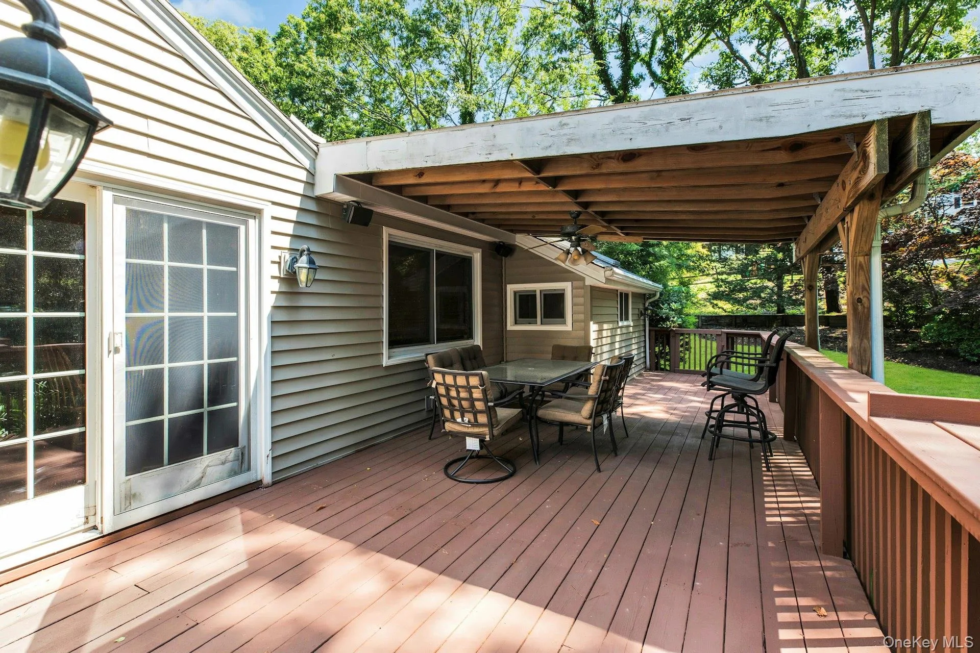 Spacious wood-finish deck featuring a partial overhead covering, offering an outdoor living area Spacious wood-finish deck featuring a partial overhead covering, offering an outdoor living area