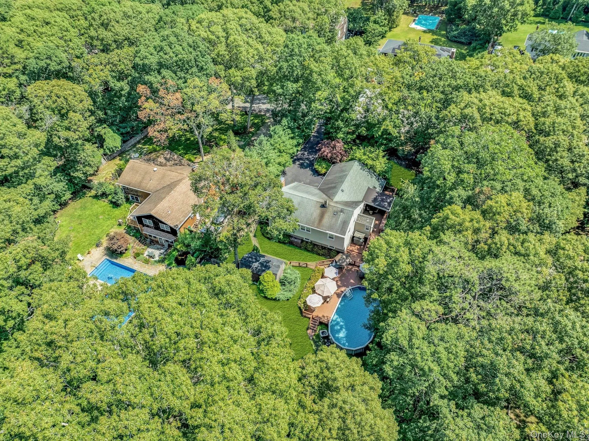 Expansive property featuring two distinct structures surrounded by mature trees Expansive property featuring two distinct structures surrounded by mature trees