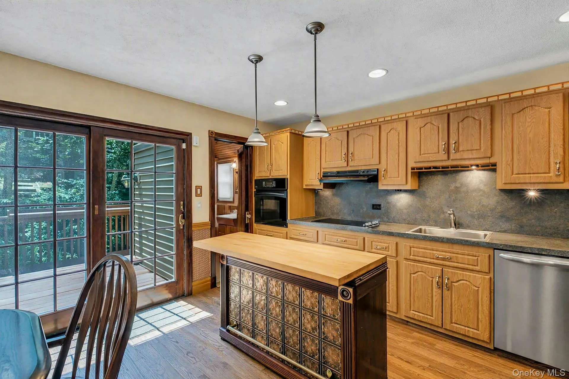 Kitchen features wood cabinetry, dark countertops, and a stainless steel dishwasher Kitchen features wood cabinetry, dark countertops, and a stainless steel dishwasher