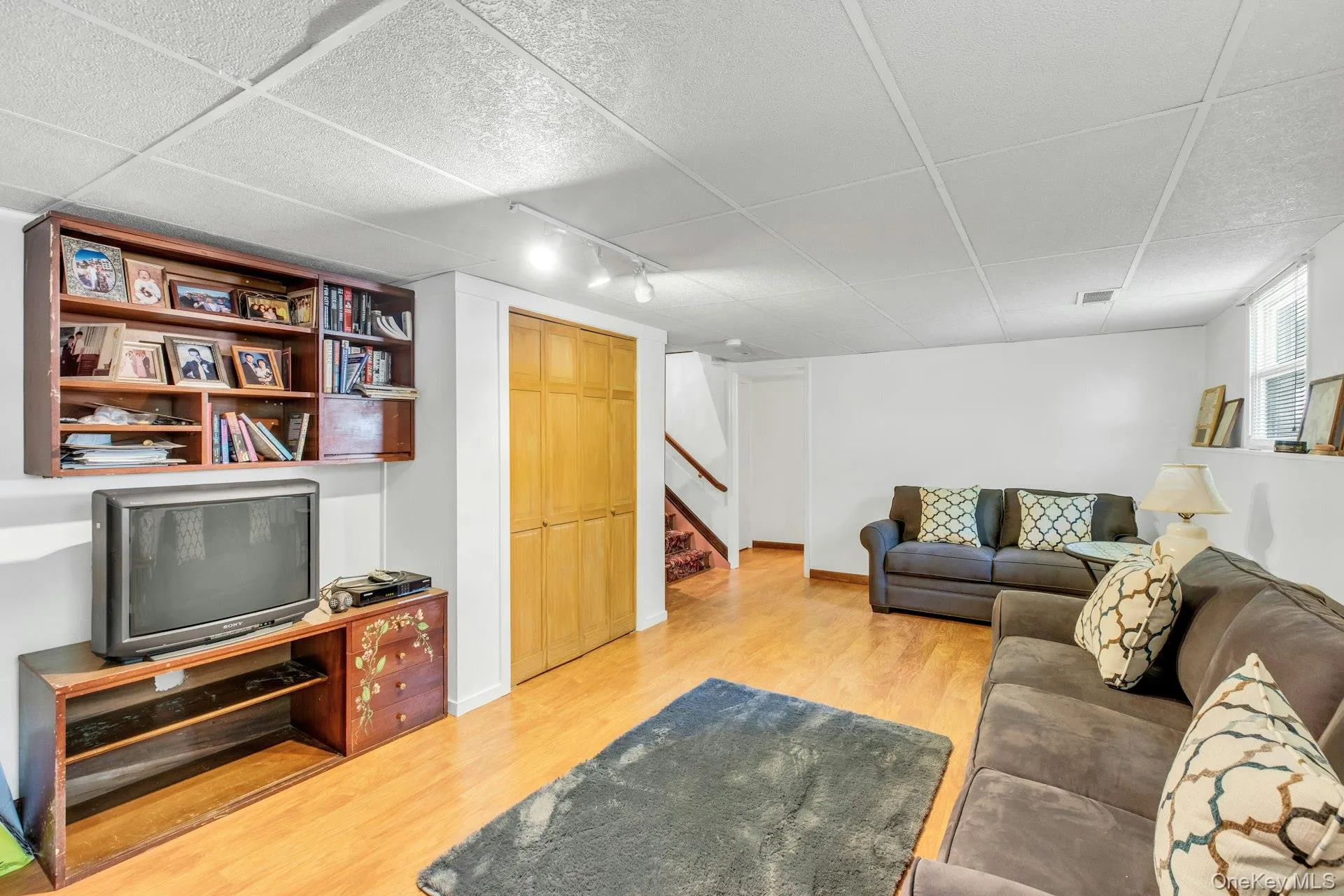 Finished living space featuring wood-finish flooring, white walls, and a drop ceiling with recessed lighting Finished living space featuring wood-finish flooring, white walls, and a drop ceiling with recessed lighting