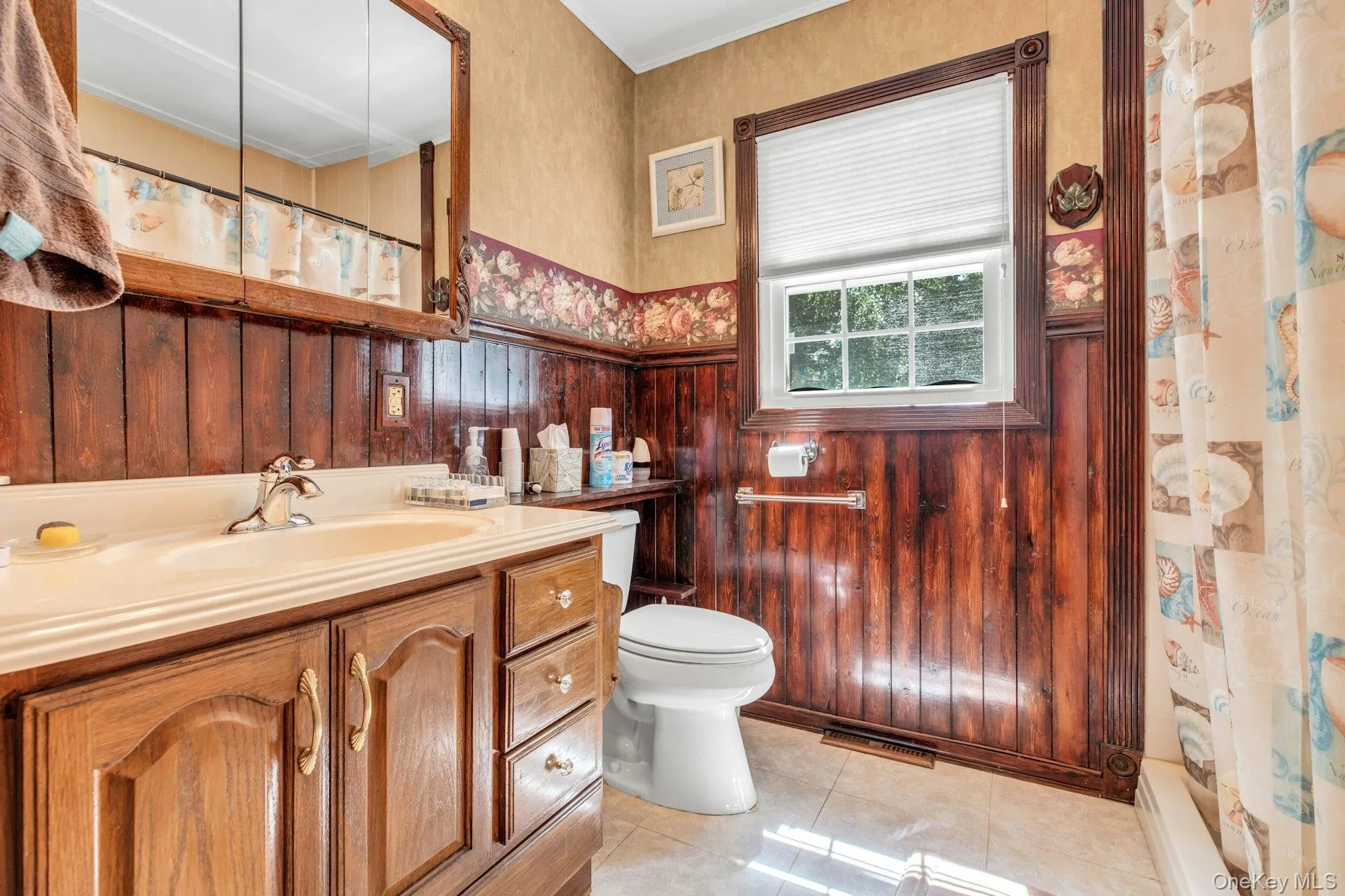 Classic bathroom featuring rich wood cabinetry with multiple drawers and storage, ceramic sink with chrome fixtures, and white ceramic toilet Classic bathroom featuring rich wood cabinetry with multiple drawers and storage, ceramic sink with chrome fixtures, and white ceramic toilet