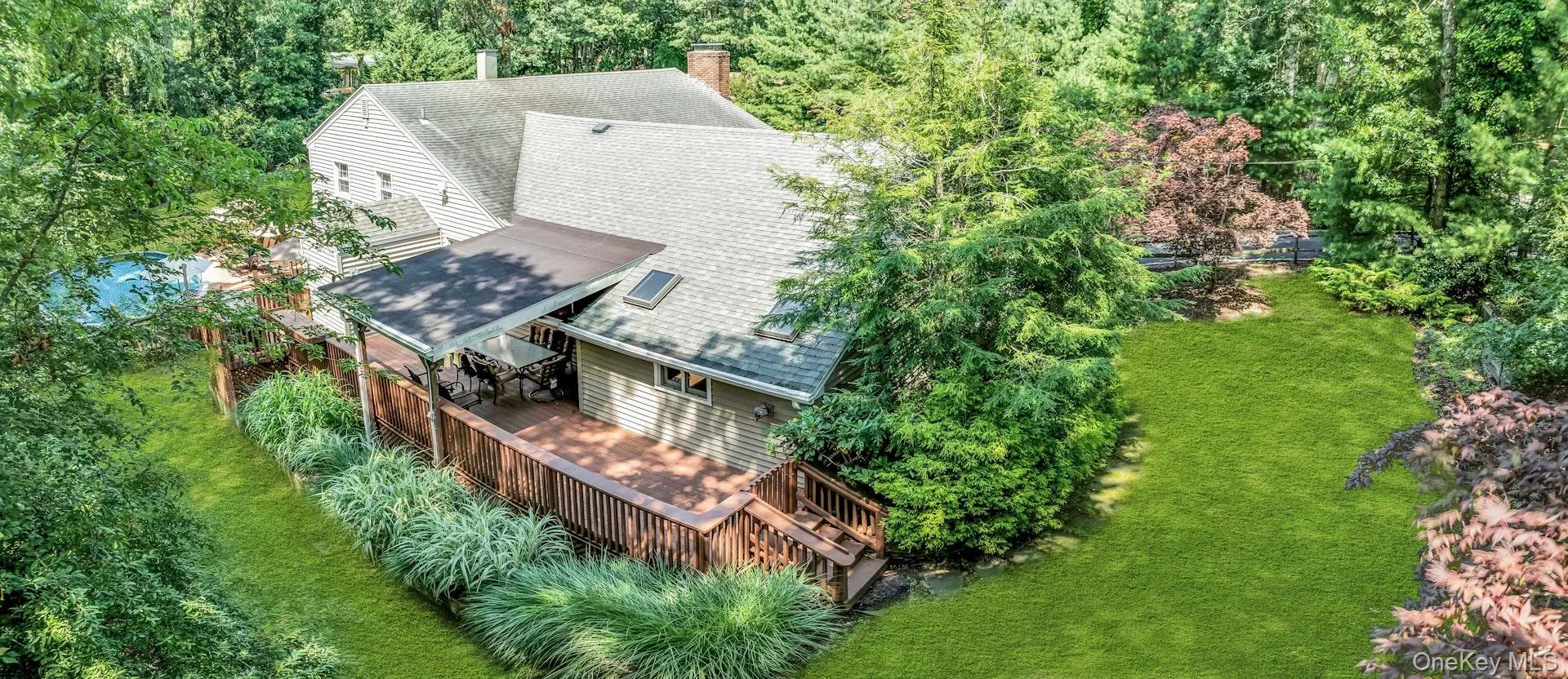 Expansive backyard oasis featuring a composite deck with integrated seating areas, mature landscaping with specimen trees and shrubs, and manicured lawn Expansive backyard oasis featuring a composite deck with integrated seating areas, mature landscaping with specimen trees and shrubs, and manicured lawn