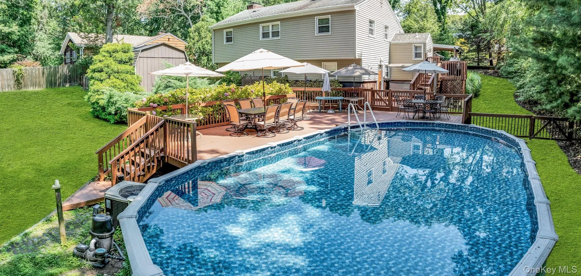 Expansive backyard featuring an above-ground pool, a multi-level wood deck, and surrounding greenery Expansive backyard featuring an above-ground pool, a multi-level wood deck, and surrounding greenery