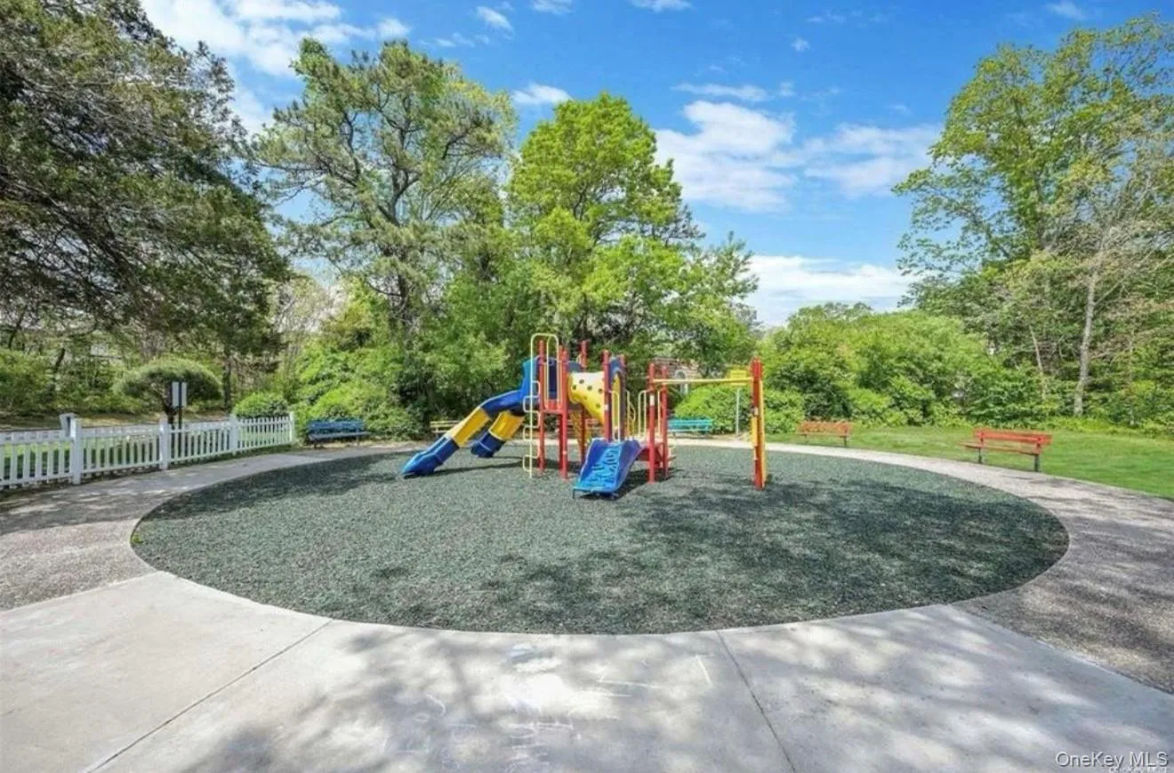 Playground area featuring a composite play structure with slides, safety surfacing, and surrounding pathways Playground area featuring a composite play structure with slides, safety surfacing, and surrounding pathways