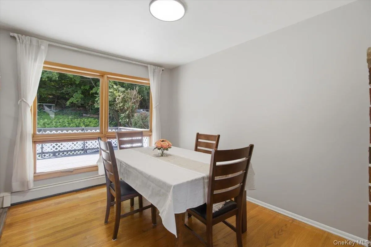 Hardwood flooring, light gray wall finish, wood-framed windows, ceiling-mounted lighting fixture, and a brick accent wall Hardwood flooring, light gray wall finish, wood-framed windows, ceiling-mounted lighting fixture, and a brick accent wall