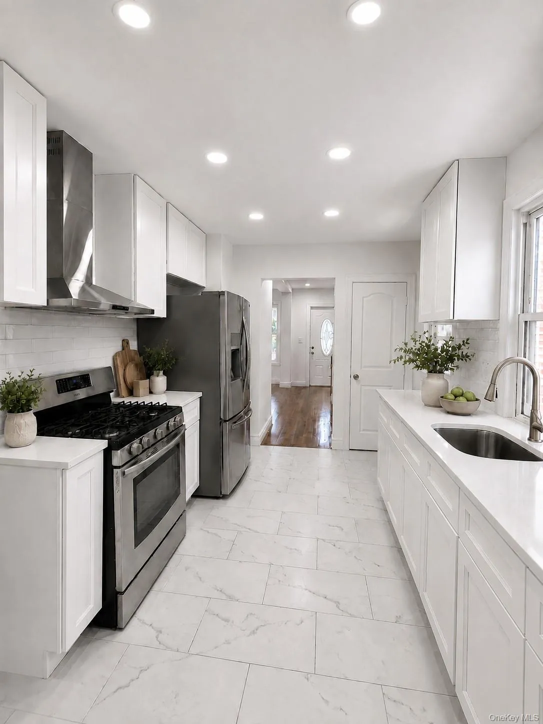 Galley kitchen featuring white cabinetry, stainless steel appliances, marble-look tile flooring, white subway tile backsplash, and recessed lighting Galley kitchen featuring white cabinetry, stainless steel appliances, marble-look tile flooring, white subway tile backsplash, and recessed lighting