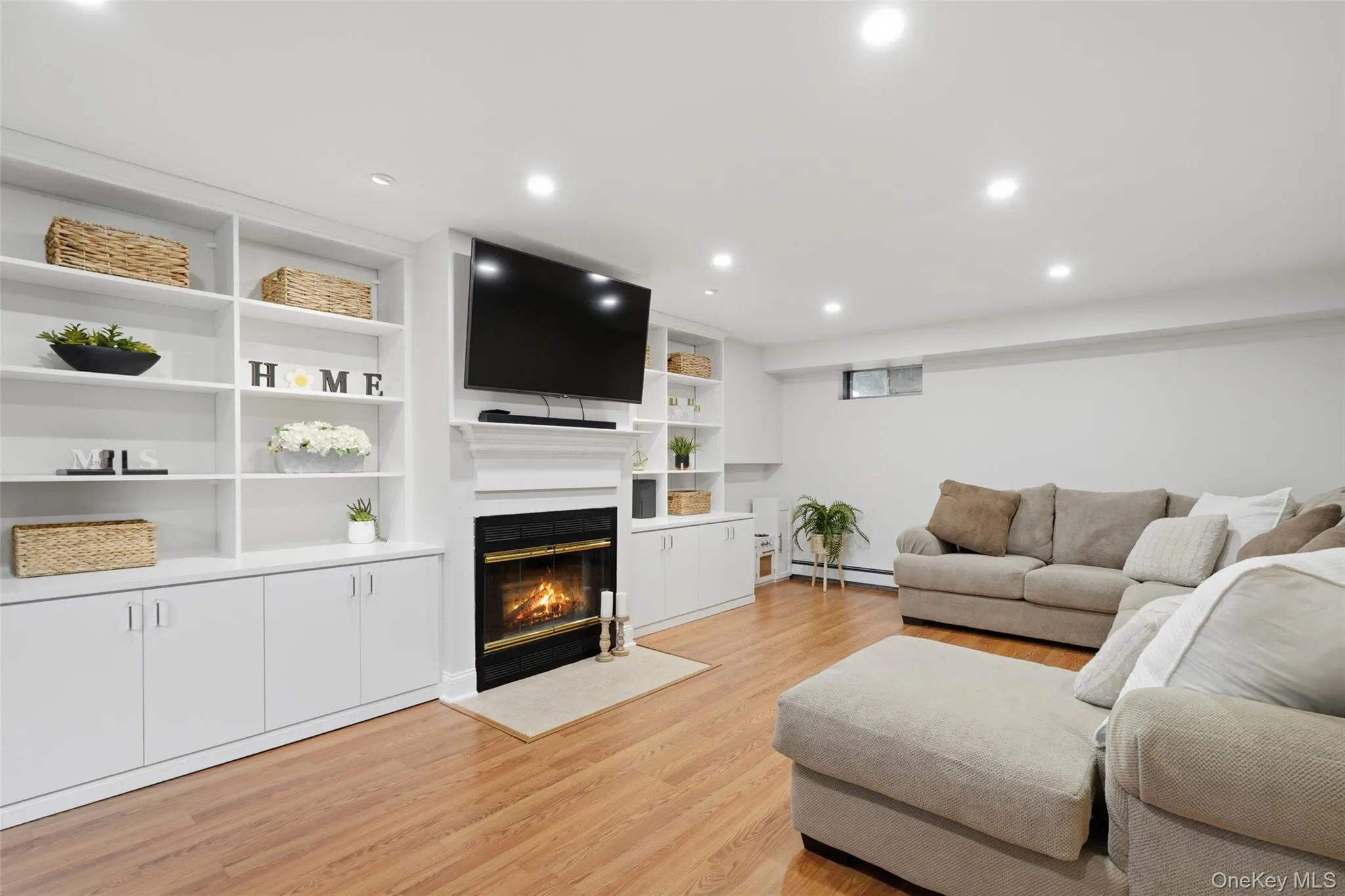 Recessed lighting, wood-finish flooring, built-in shelving, built-in cabinetry, and a fireplace with a mantel Recessed lighting, wood-finish flooring, built-in shelving, built-in cabinetry, and a fireplace with a mantel