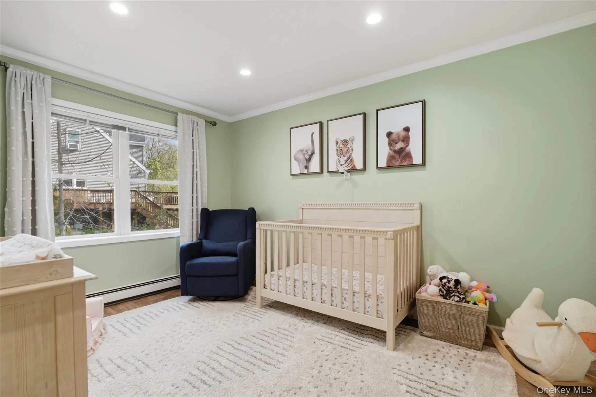 Recessed lighting illuminates this room, featuring wood-finish flooring, a large window, and crown molding Recessed lighting illuminates this room, featuring wood-finish flooring, a large window, and crown molding
