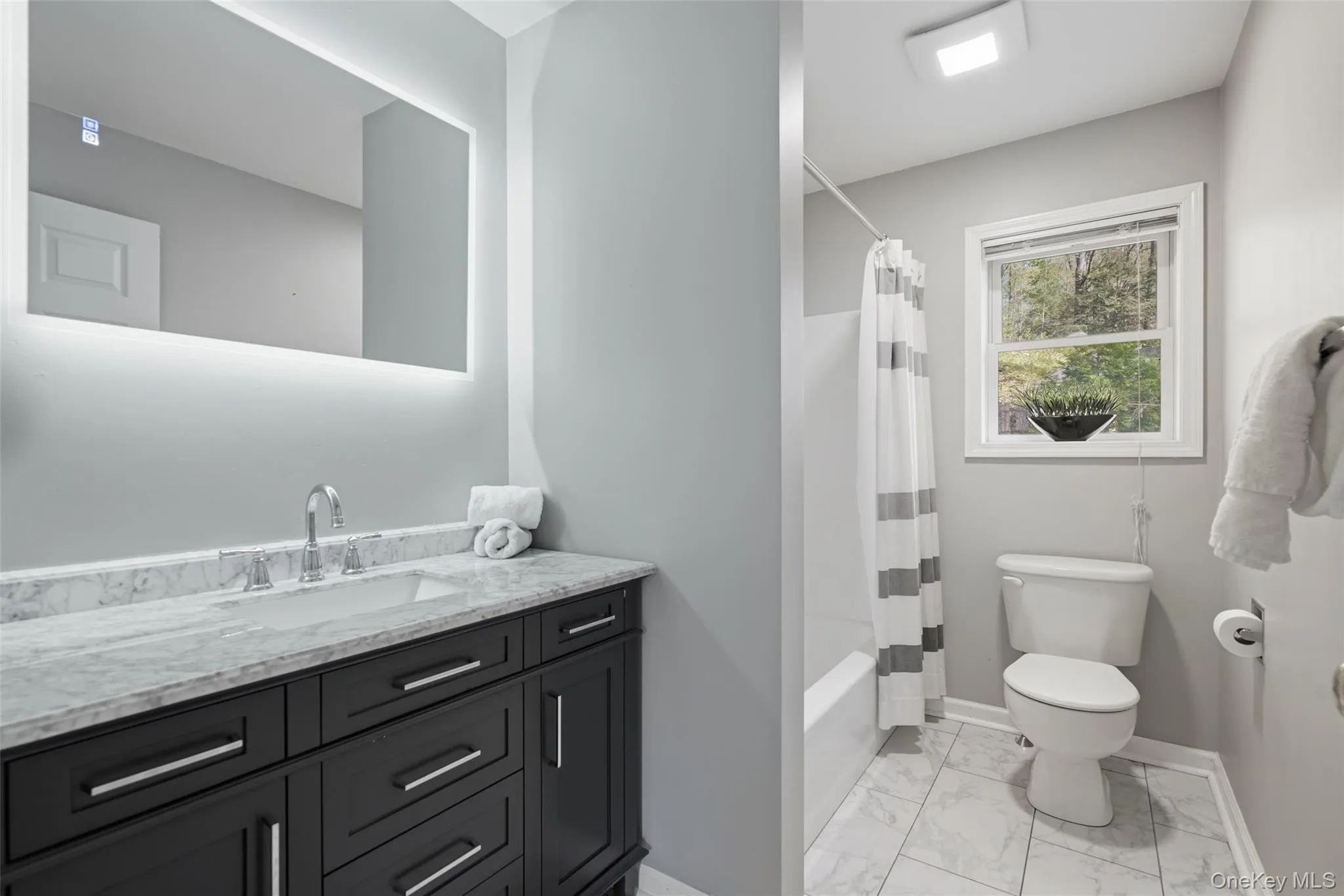 Vanity with an integrated rectangular sink, stone countertop, chrome faucet, and under-mirror lighting Vanity with an integrated rectangular sink, stone countertop, chrome faucet, and under-mirror lighting