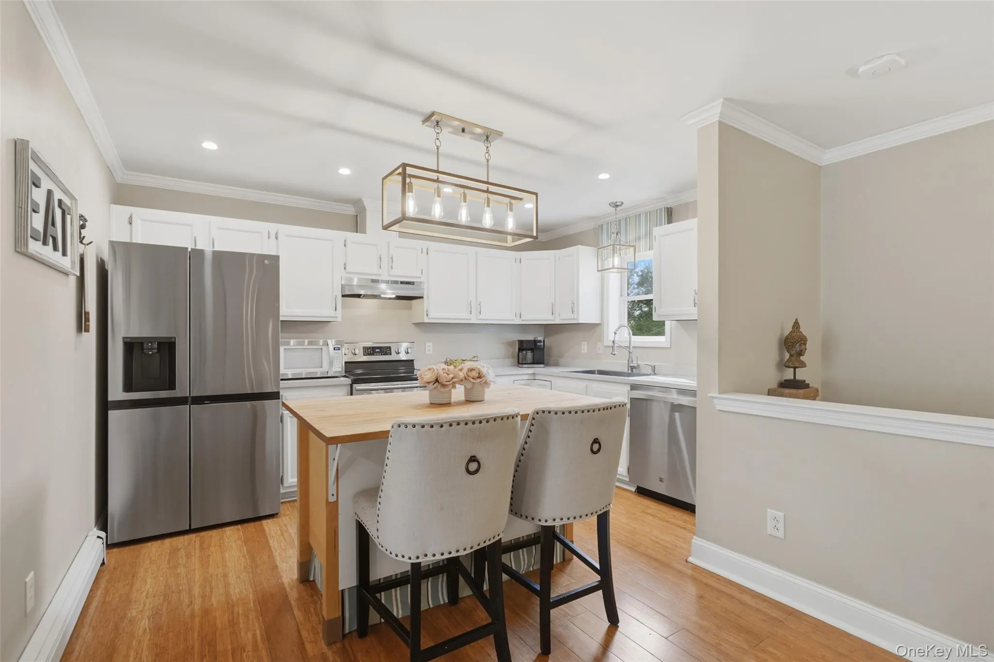 Kitchen featuring white cabinetry, stainless steel appliances, a wood-finish island, and recessed lighting Kitchen featuring white cabinetry, stainless steel appliances, a wood-finish island, and recessed lighting
