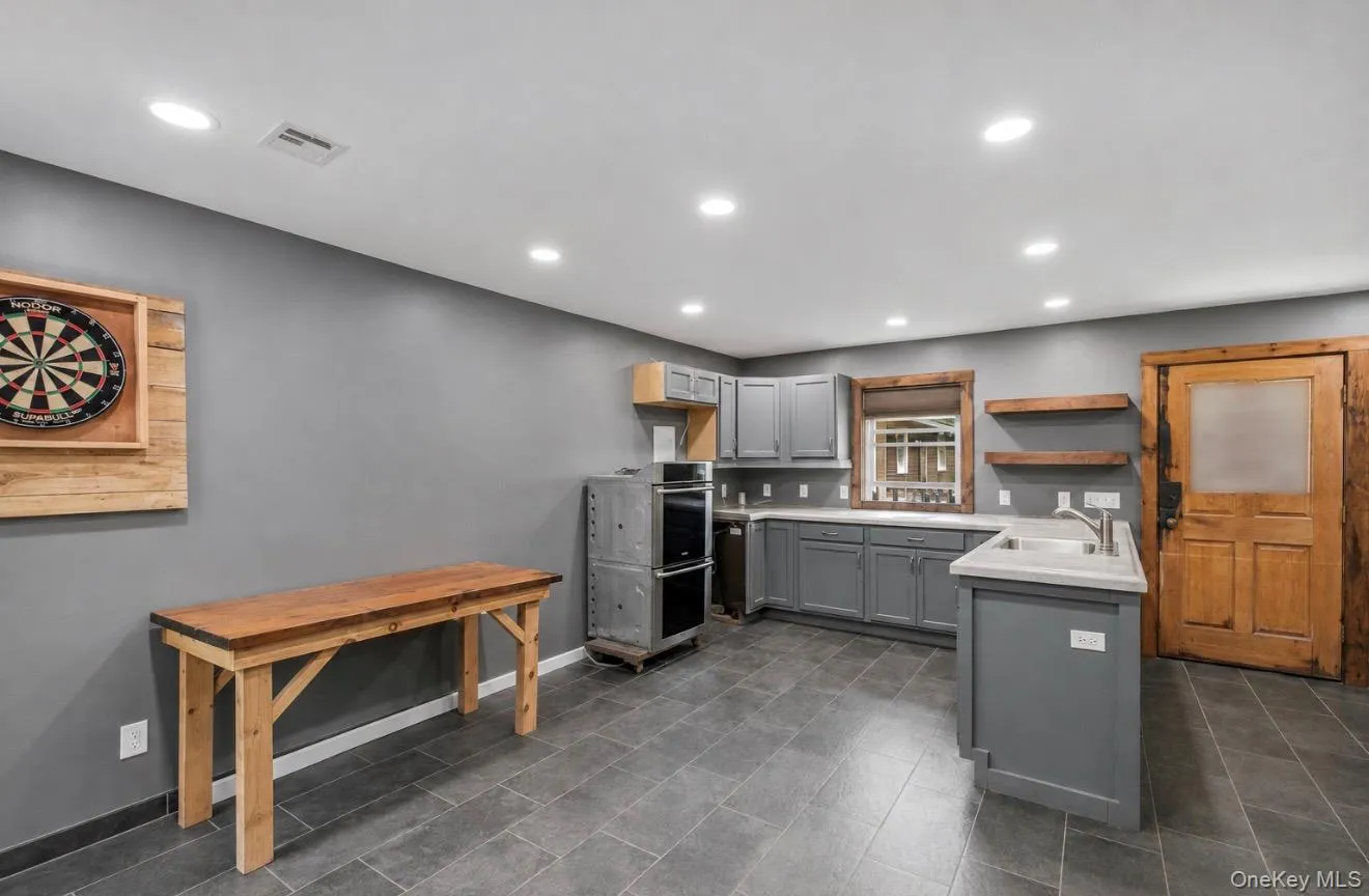 Spacious kitchen with grey cabinetry, stainless steel appliance, slate-finish flooring, recessed lighting throughout, and wood-frame architectural details Spacious kitchen with grey cabinetry, stainless steel appliance, slate-finish flooring, recessed lighting throughout, and wood-frame architectural details